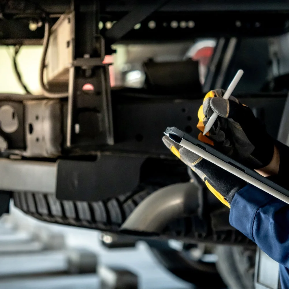 Technician performing a preventative propshaft inspection on a heavy commercial vehicle.