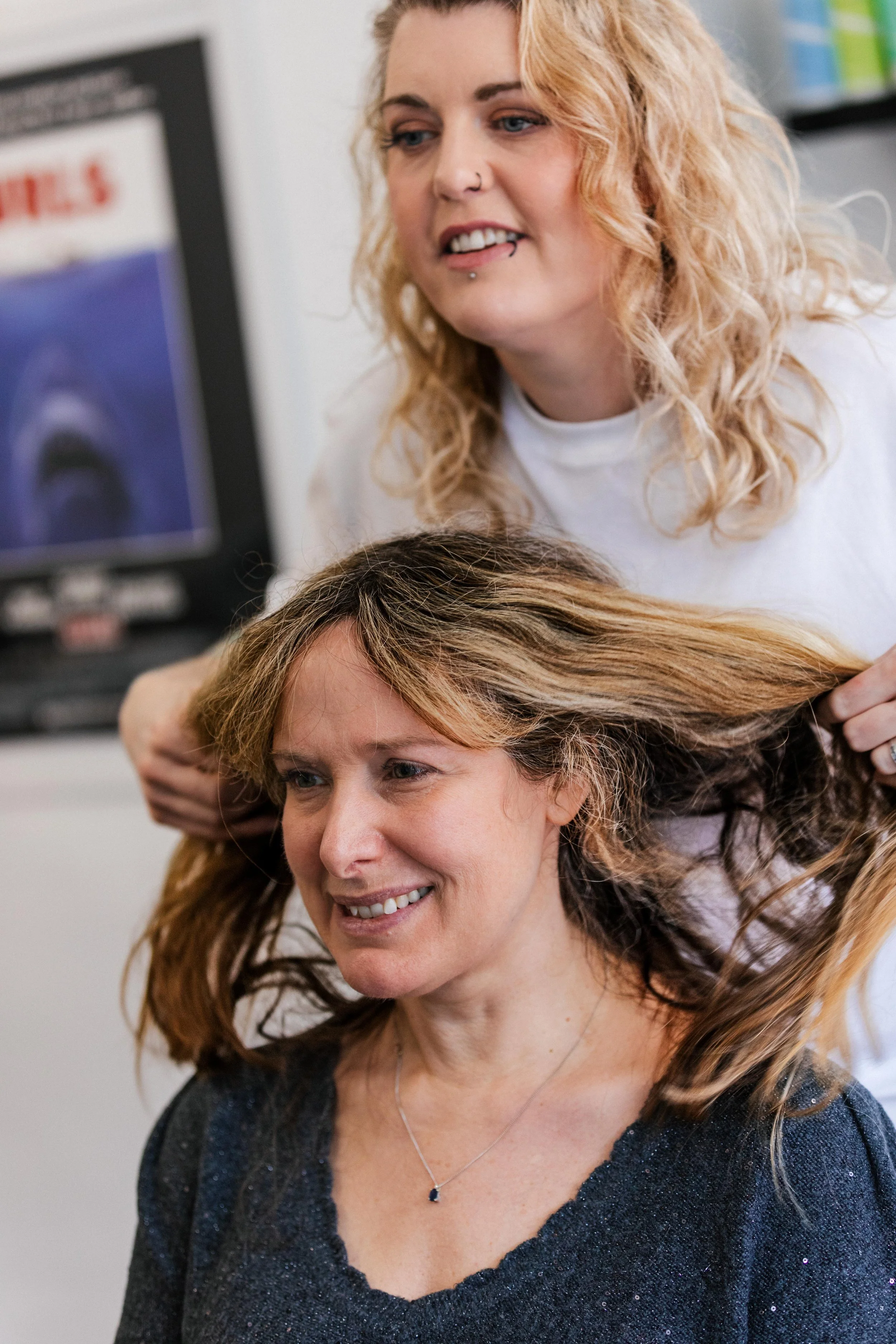 A woman with long hair getting her hair styled by a hairstylist in a salon or spa.