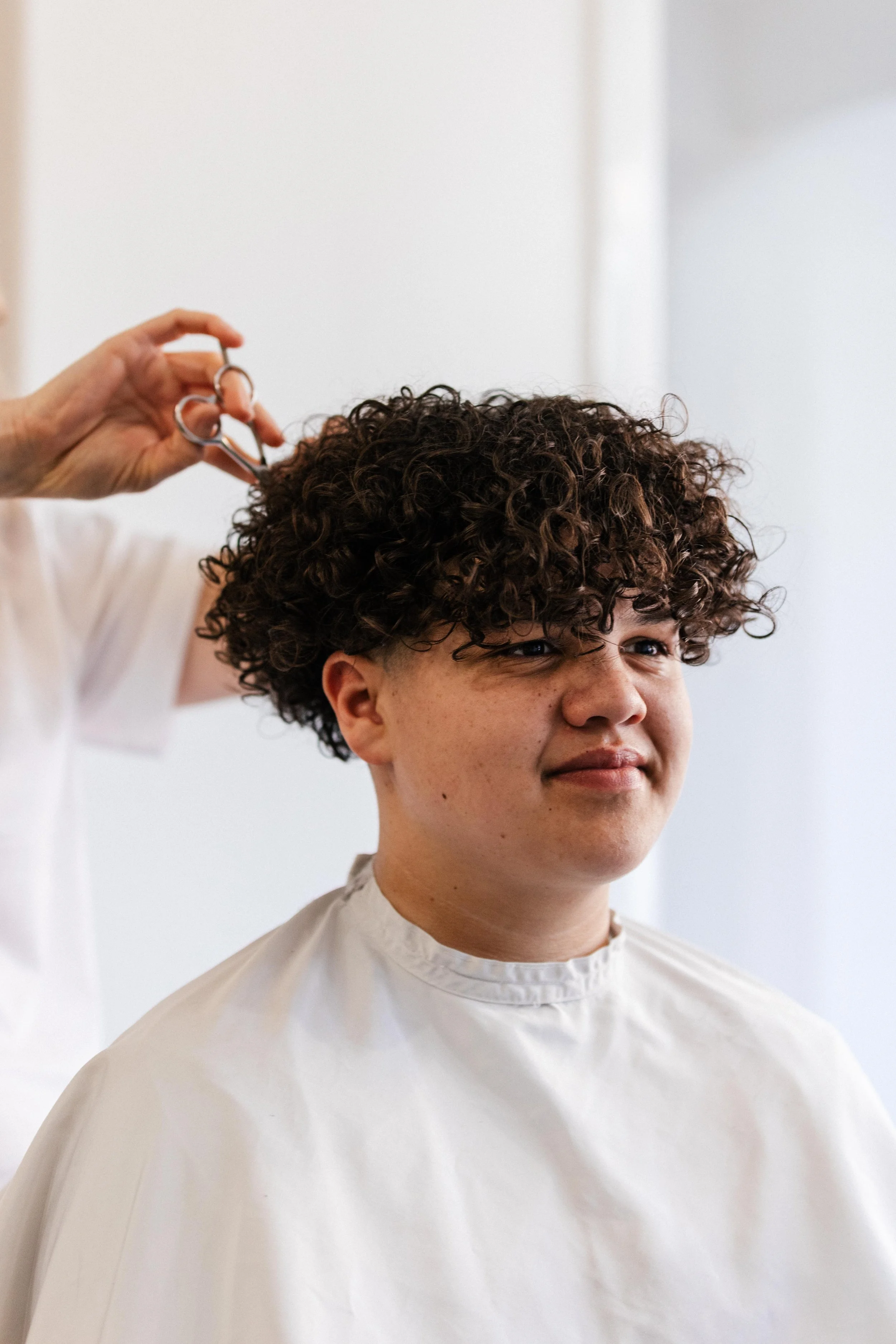 Person with curly hair getting a haircut in a salon