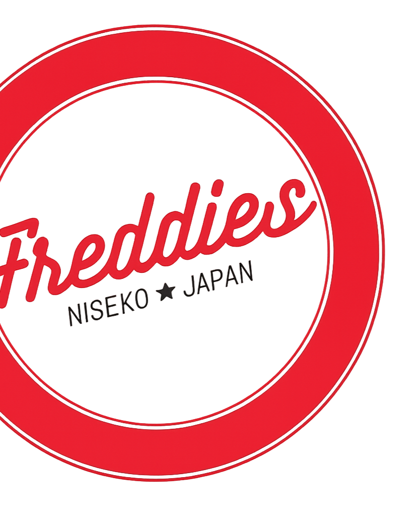 Close-up of a red and white circular sticker or logo with the word 'Freddies' in red script, and 'NISEKO JAPON' below it, indicating a brand from Niseko, Japan.