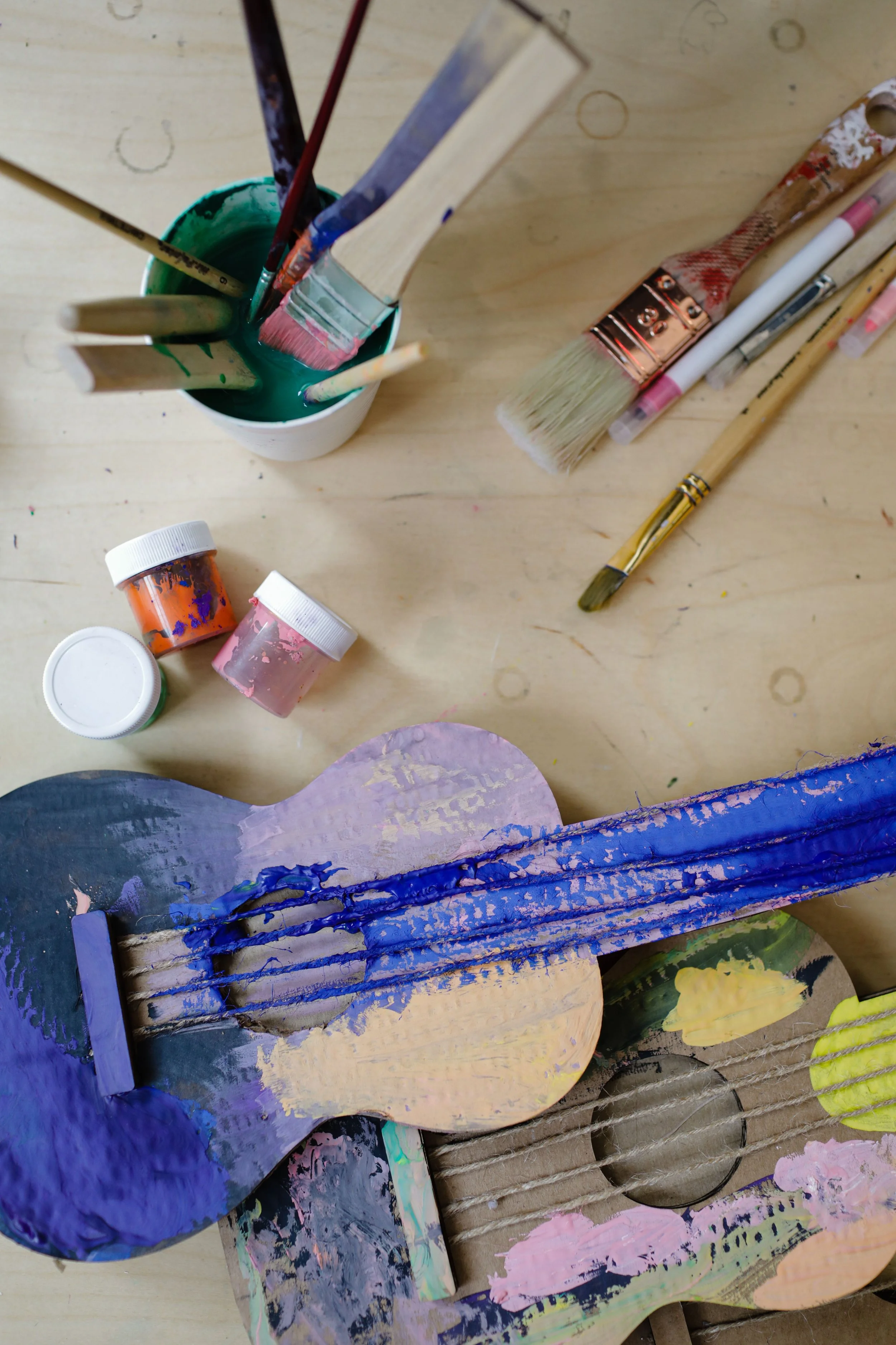 A CASA workshops de pintura e arte no Barreiro. Material de artesanato com tinta e pincéis, tábua de pintura, e pedaços de papel ou madeira pintados com cores variadas
