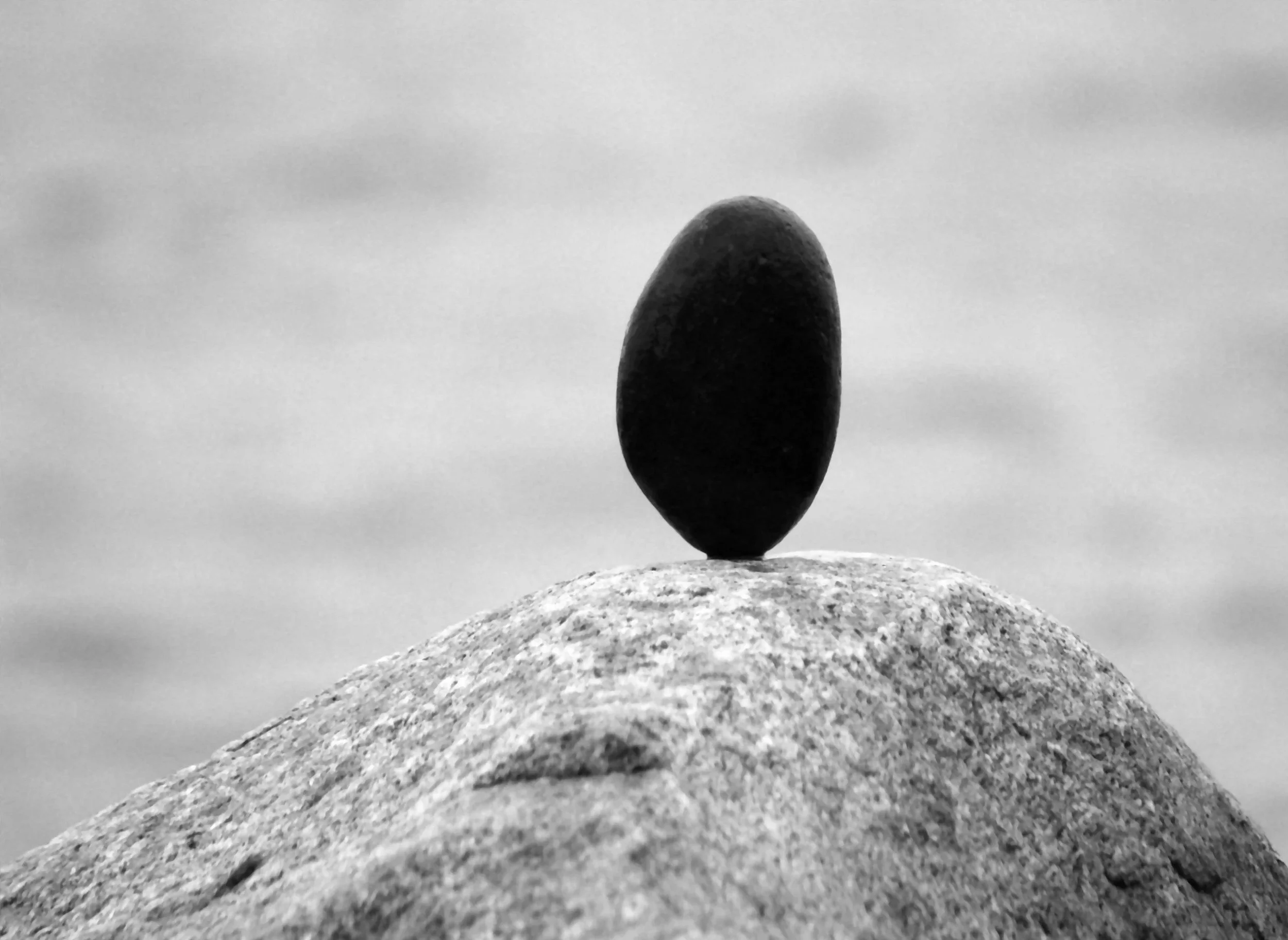 Black and white image of a single stone balanced on a rock, symbolising discernment, commitment, and selective partner choice in dating.