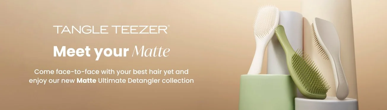 Display of three Tangle Teezer hair detangling brushes in white, green, and beige positioned on pastel-colored stands, with branding and promotional text highlighting the Matte Ultimate Detangler collection.