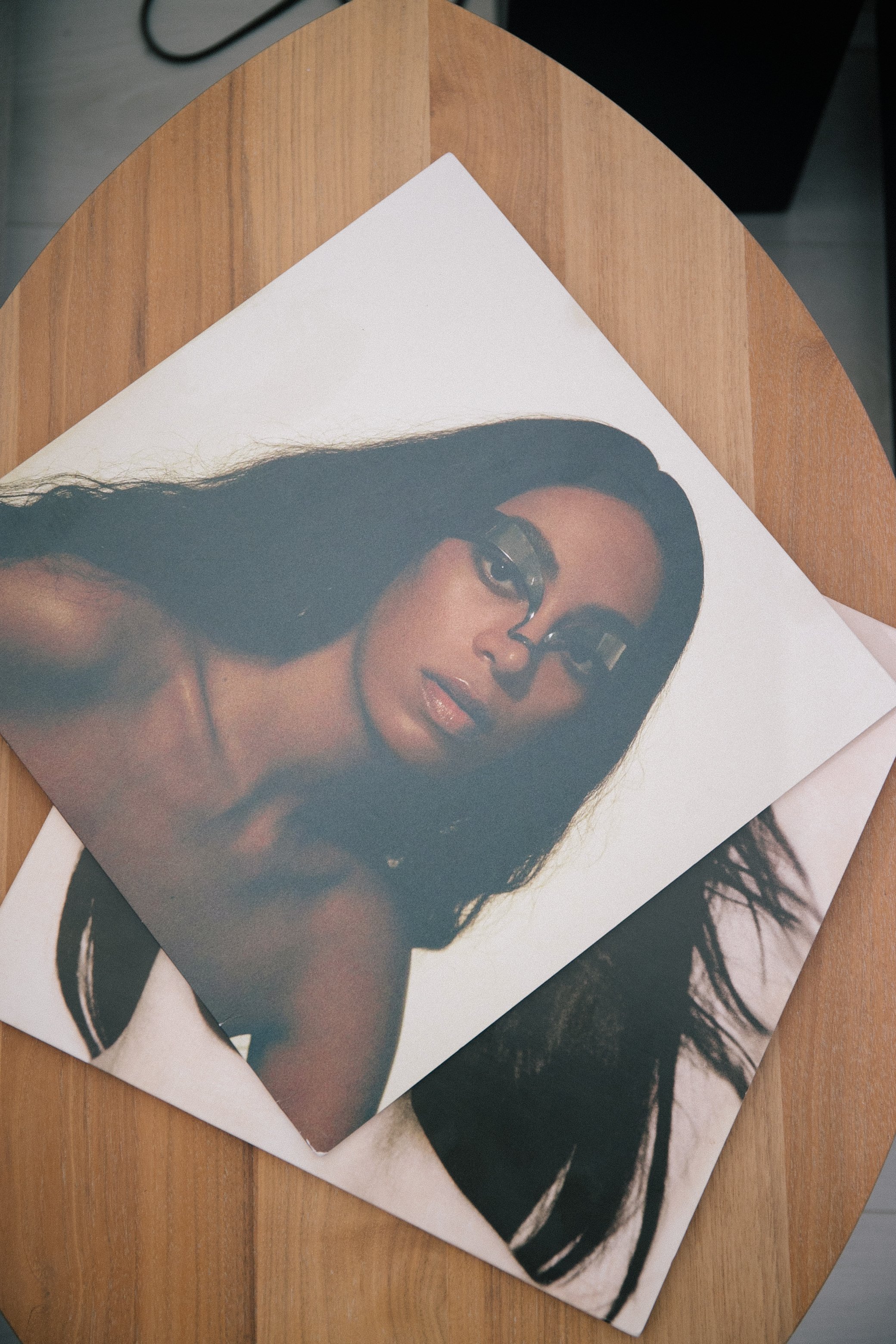 Vinyls of the artist Solange resting on a wooden surface. The cover shows her with long dark hair, glasses, and makeup.