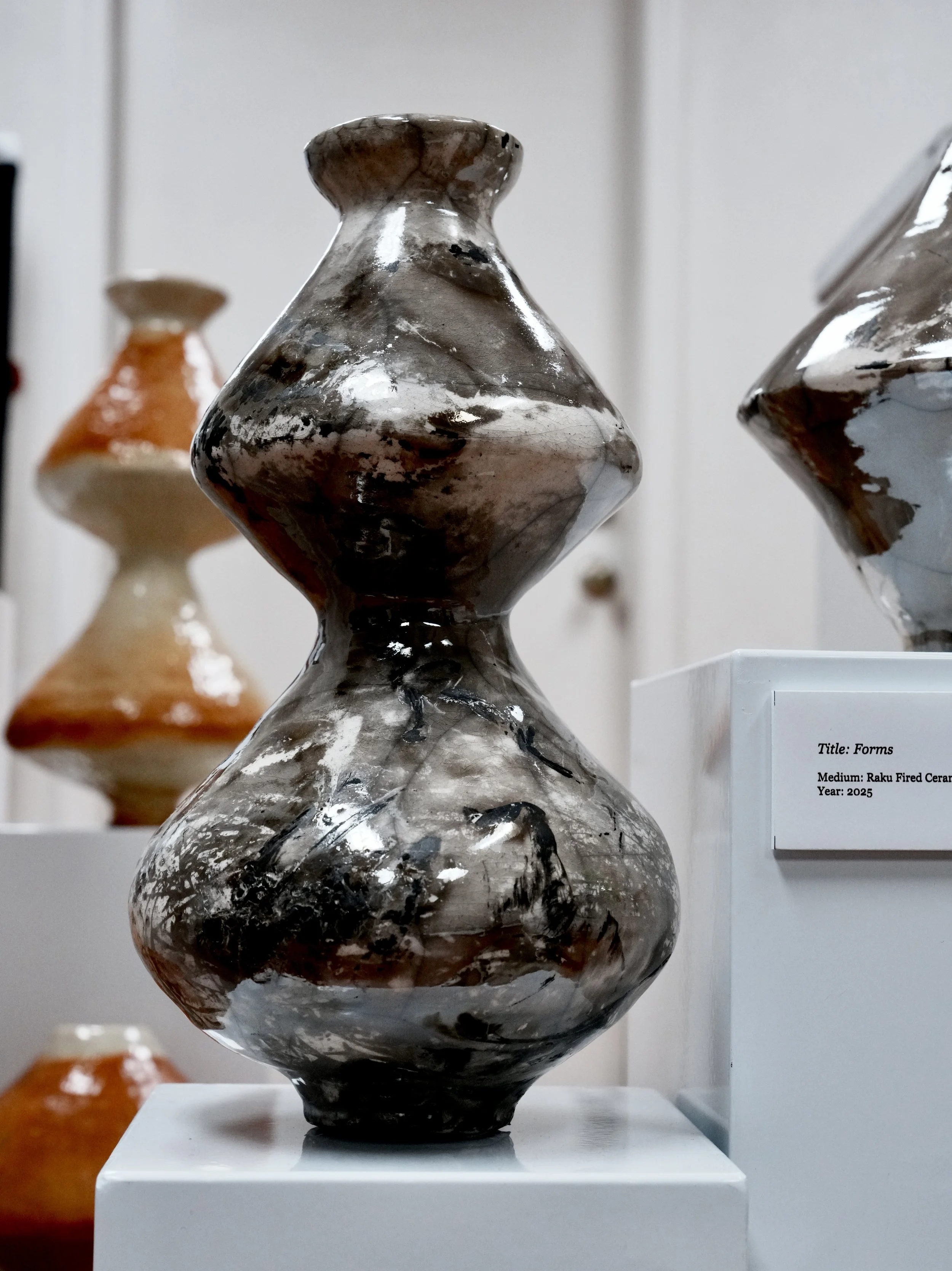 Ceramic sculpture titled 'Forms' displayed on a white pedestal, made with Raku fired ceramic, year 2025.