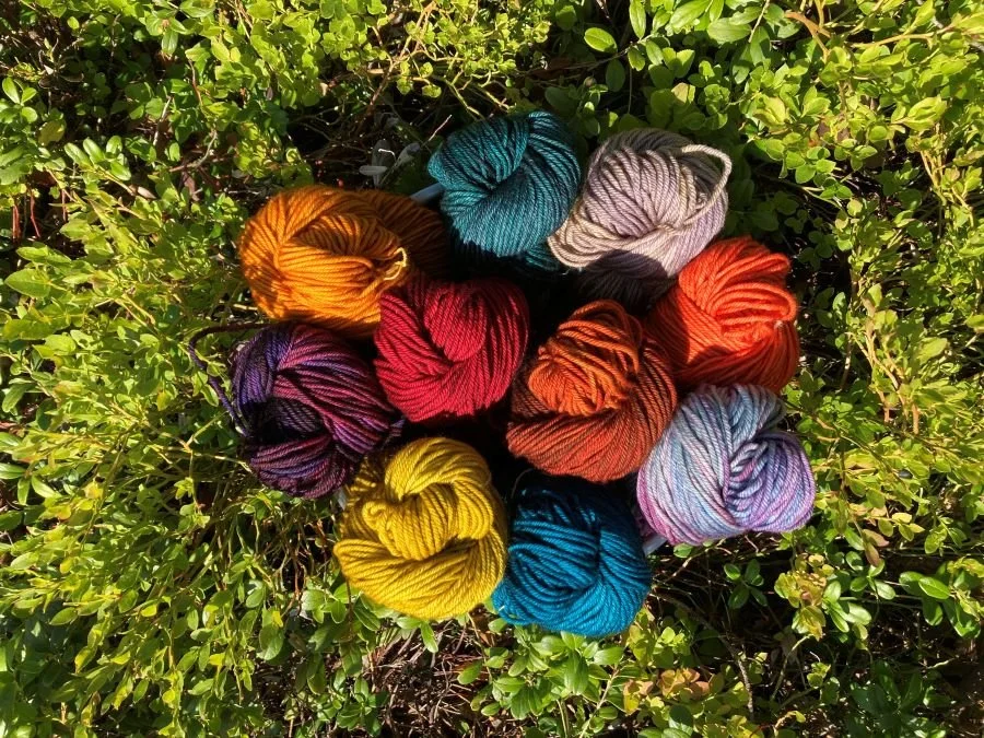 Värikkäitä lankakeriä nurmikon päällä.