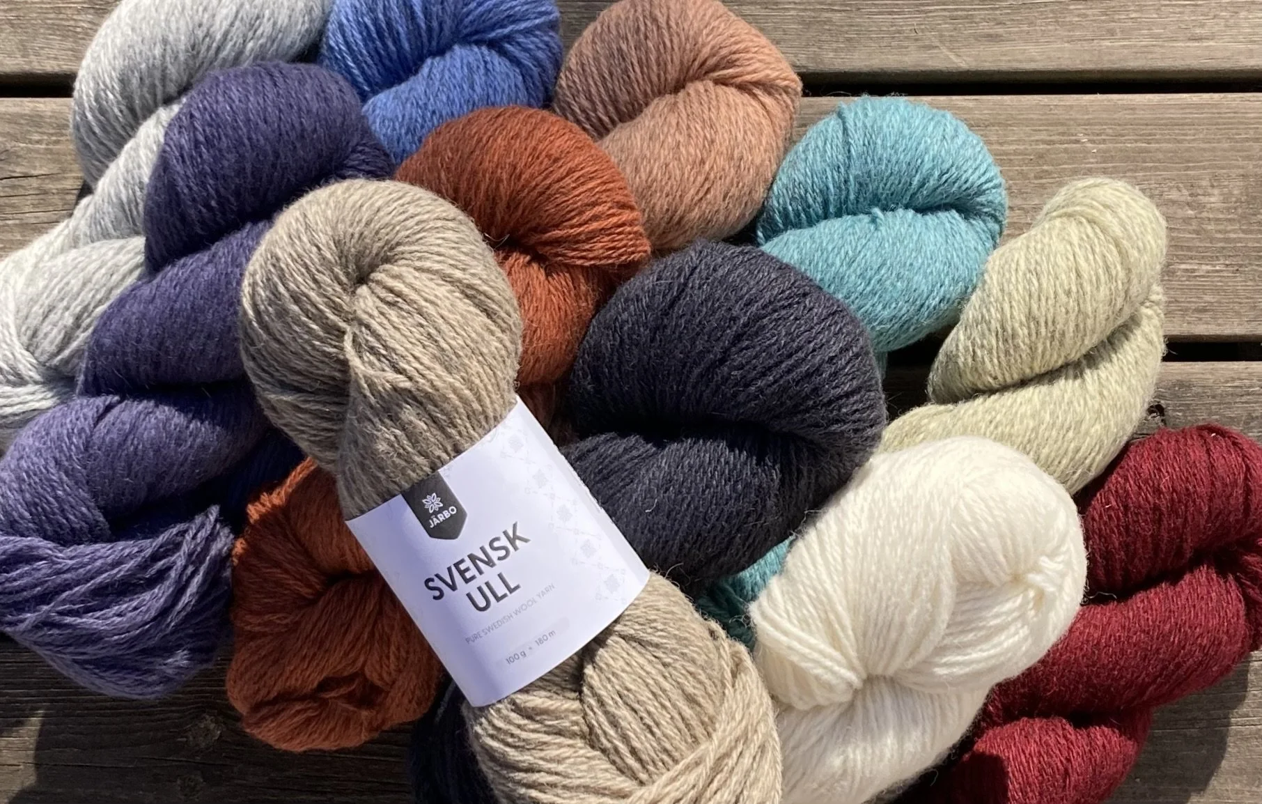 Useiden värikkäiden puuvillalankakerien kasattu kasa puisella pöydällä.