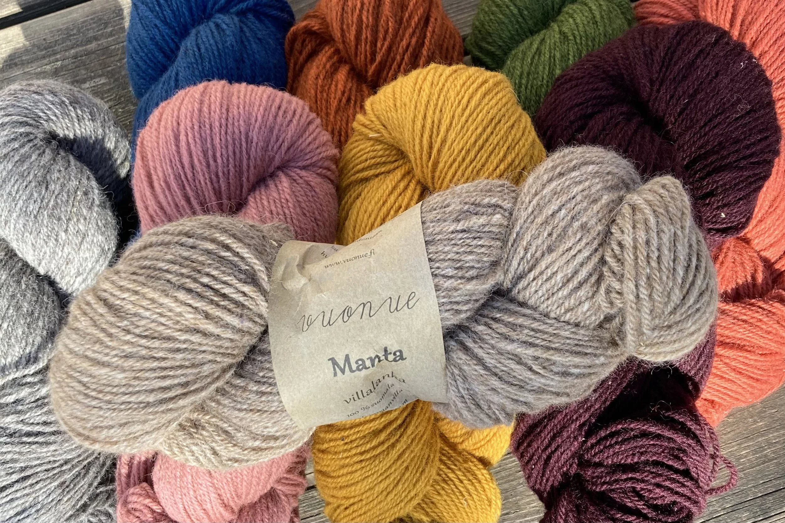 Lankoja eri väreissä ja villalankaa, jossa on paperinen etiketti.