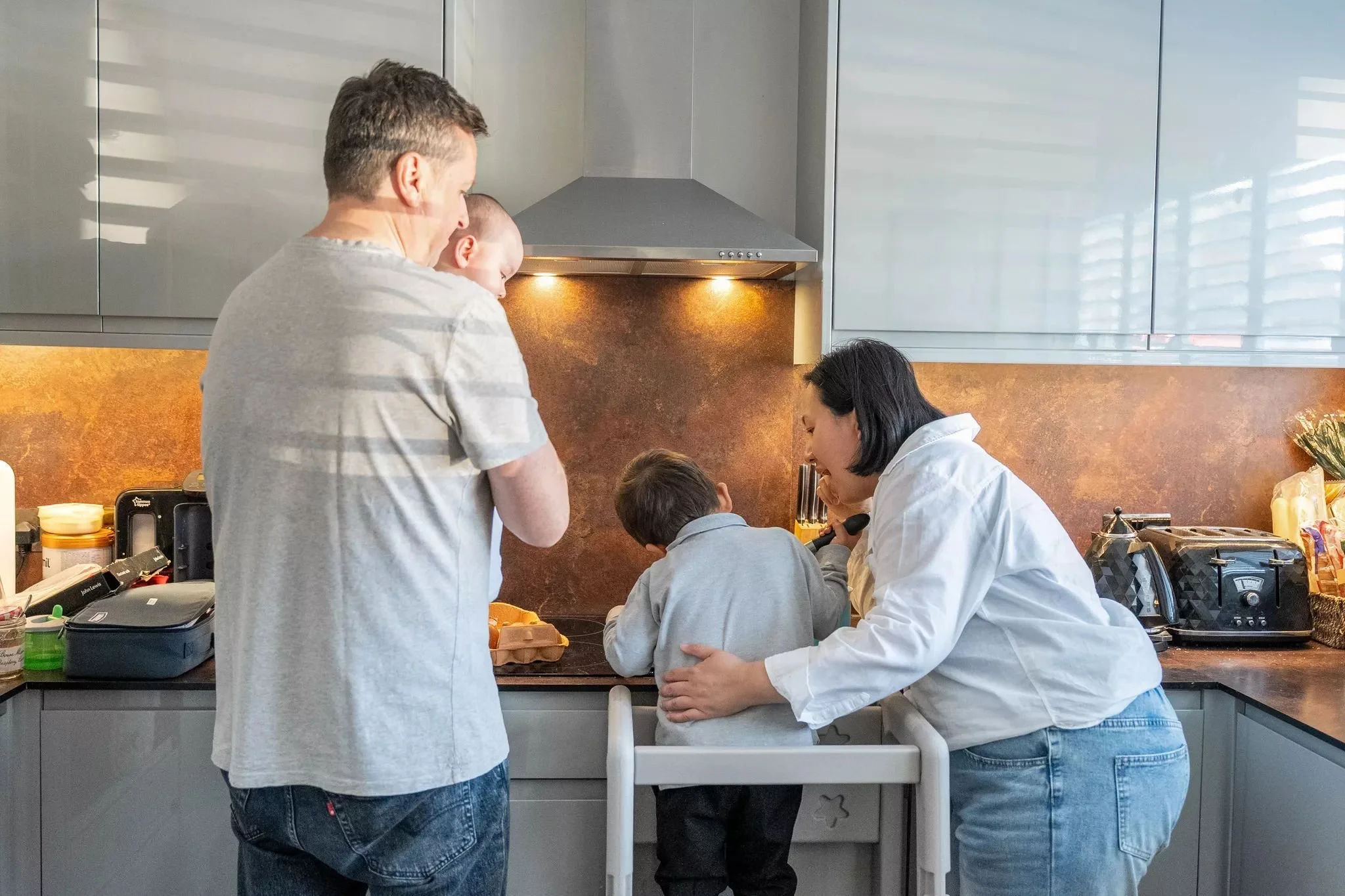 tews whole family kitchen chaos facing away eating meal prep helping.jpg