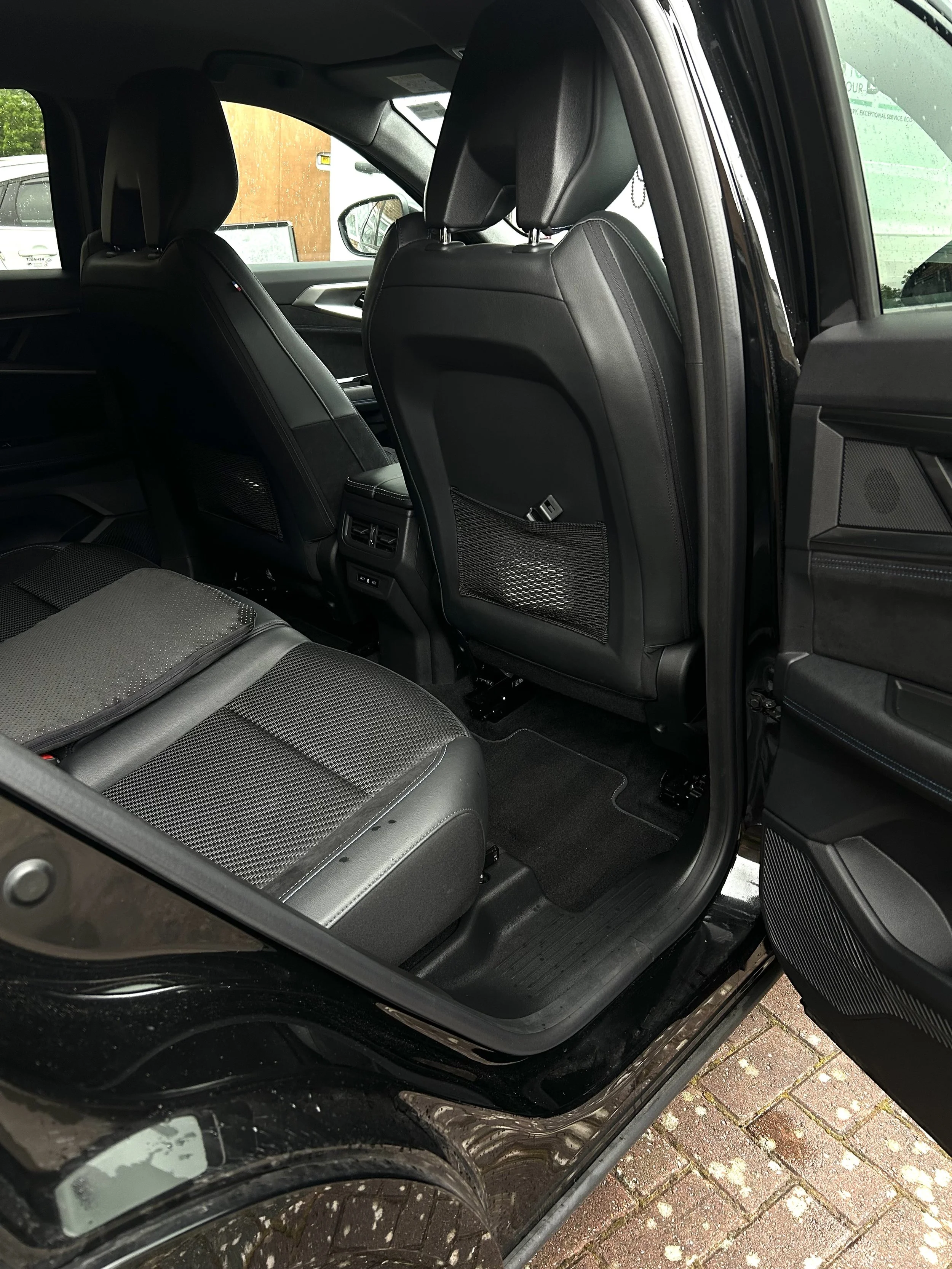 The interior of a black SUV showing black leather seats and back pockets on the front seats.