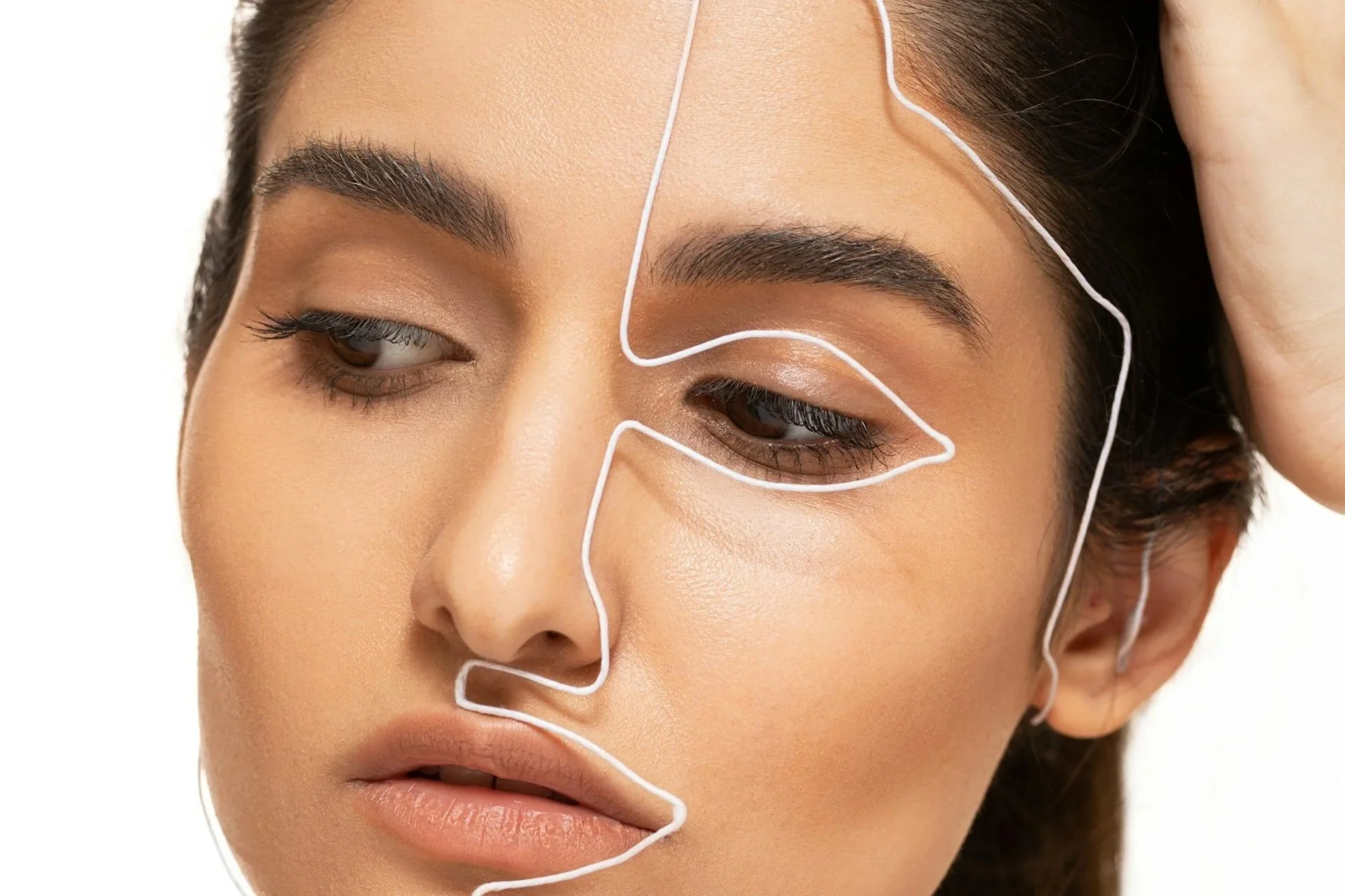 Close-up of a woman's face with white facial mapping lines over her forehead, eyebrows, and cheek.