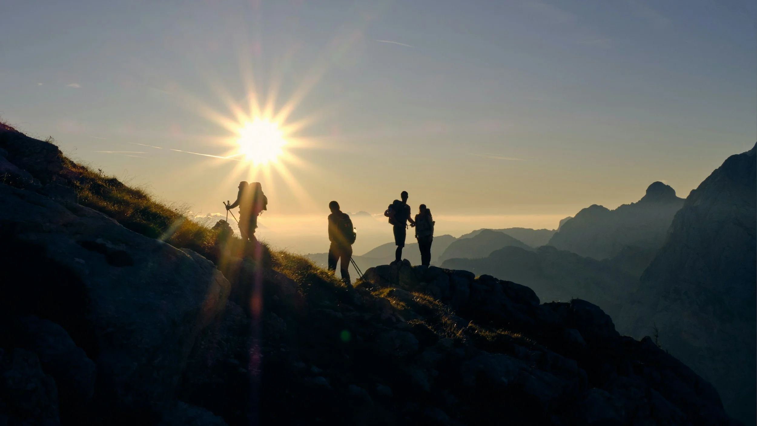 Groupe de randonneurs au coucher de soleil dans une vallée montagneuse.