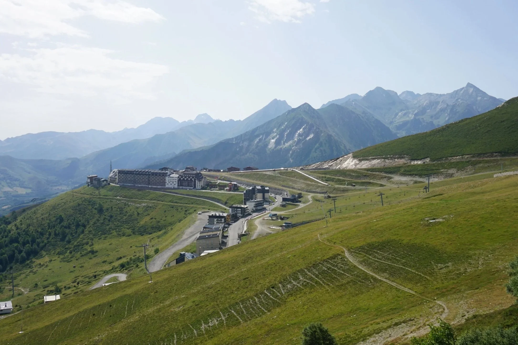 Paysage de montagnes avec un village en contrebas et des pistes de ski ou sentiers à proximité.