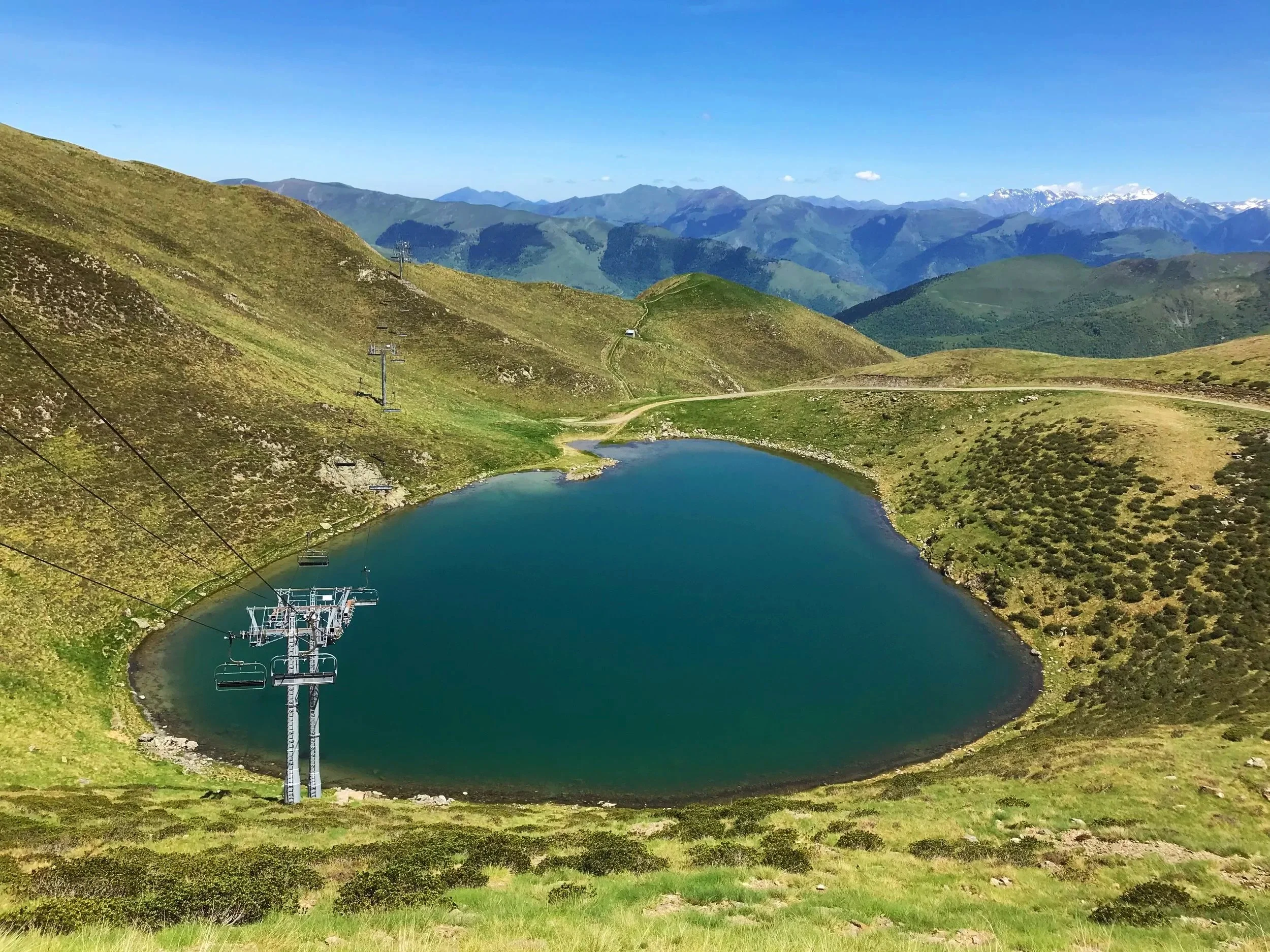 Vue panoramique de montagnes avec un lac en premier plan et des chaises mécaniques pour ski ou randonnée