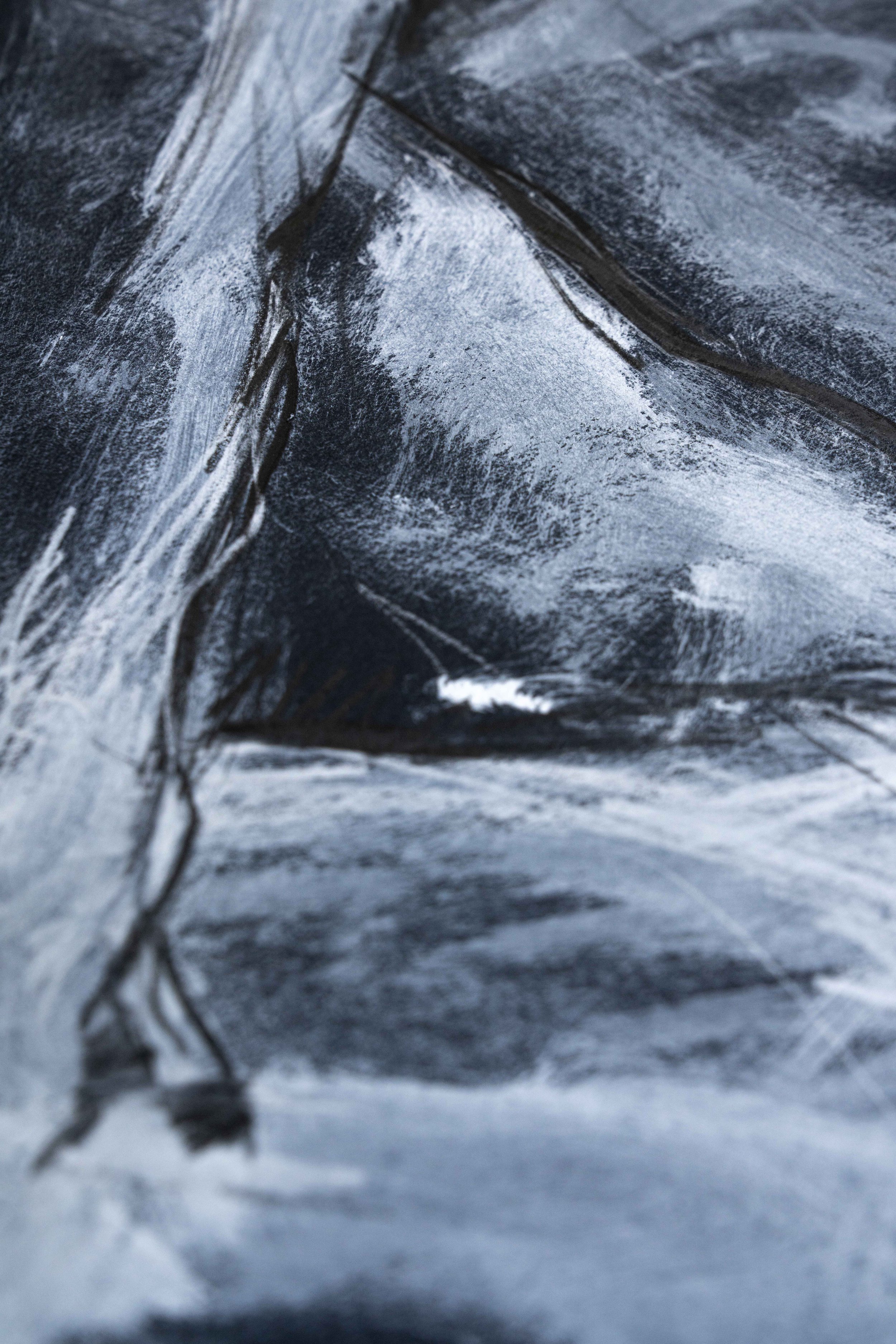 Detail einer Körperzeichnung auf schwarzem Grund. Weisse und graue Spuren werden verwischt, überzeichnet und verdichtet. Damaris Tobler zeigt damit einen experimentellen Zugang zur figurativen Zeichnung und zum Arbeiten mit Licht und Schatten.