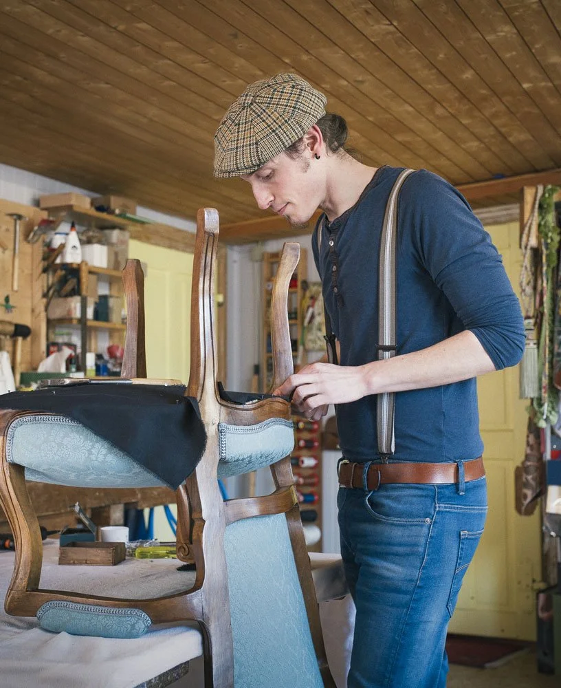 Antikpolsterer Simon Tobler bei der Restaurierung eines historischen Stuhls in der Polsterei Saienbrücke in Urnäsch – traditionelles Polsterhandwerk im Appenzellerland, Ostschweiz.