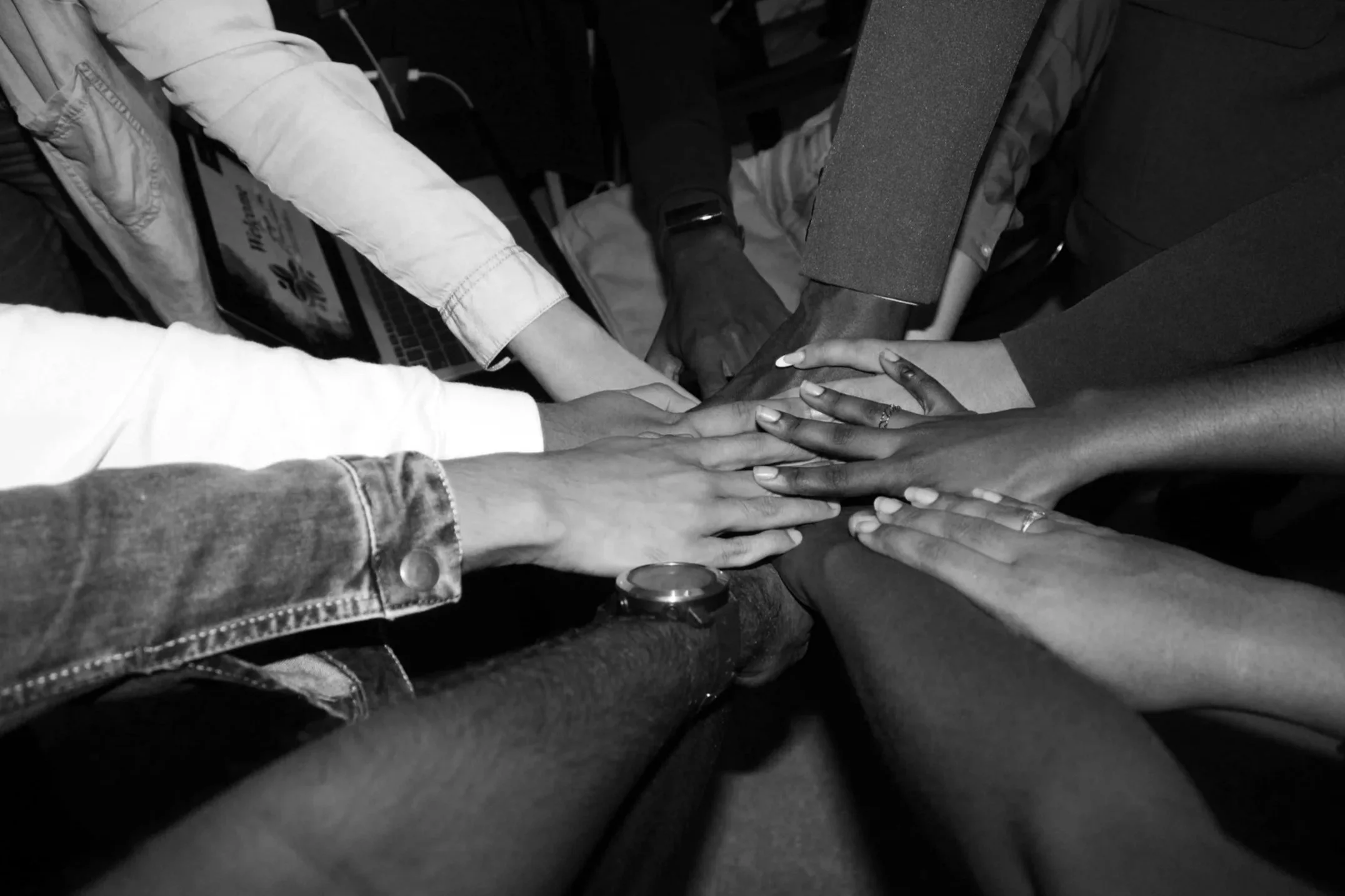 Multiple hands of diverse individuals stacked together in a show of unity and teamwork.
