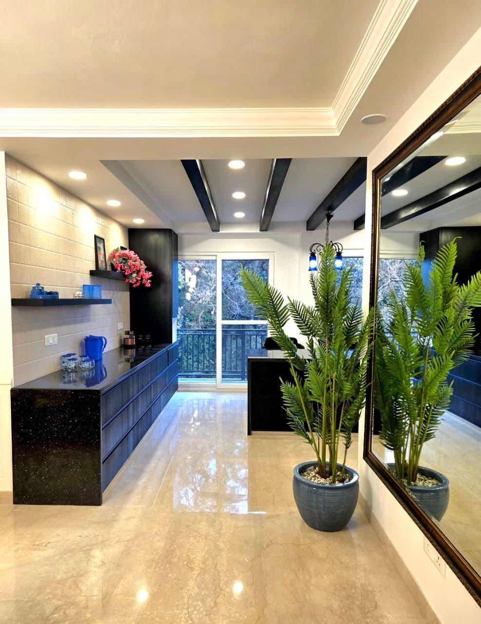 Modern living room with beige marble floor, large mirror on the right wall, tall green plant in a pot, black ceiling beams, sliding glass door leading to balcony.