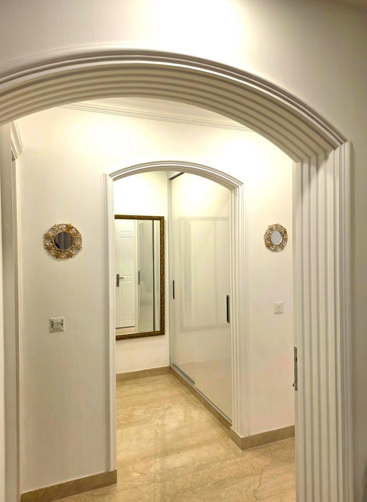 View of an entryway with an archway, mirror on the wall, and a sliding closet door.