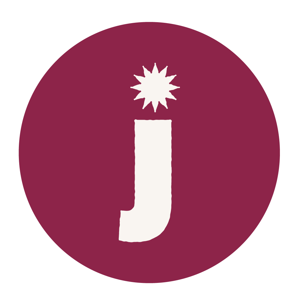 Un logo circulaire avec un fond bordeaux, un symbole de lettre 'J' en blanc au centre, accentué par une étoile ou une explosion située au-dessus de la barre supérieure de la lettre.