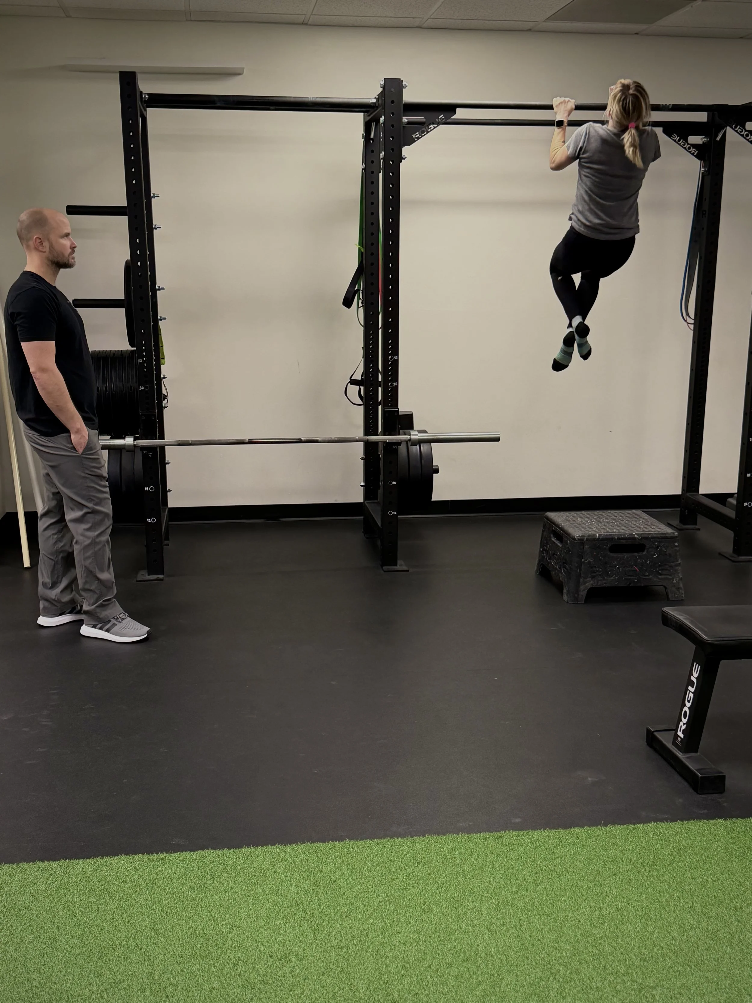 Jessica doing pullups with a personal trainer at The Movement Lab in Raleigh, NC.