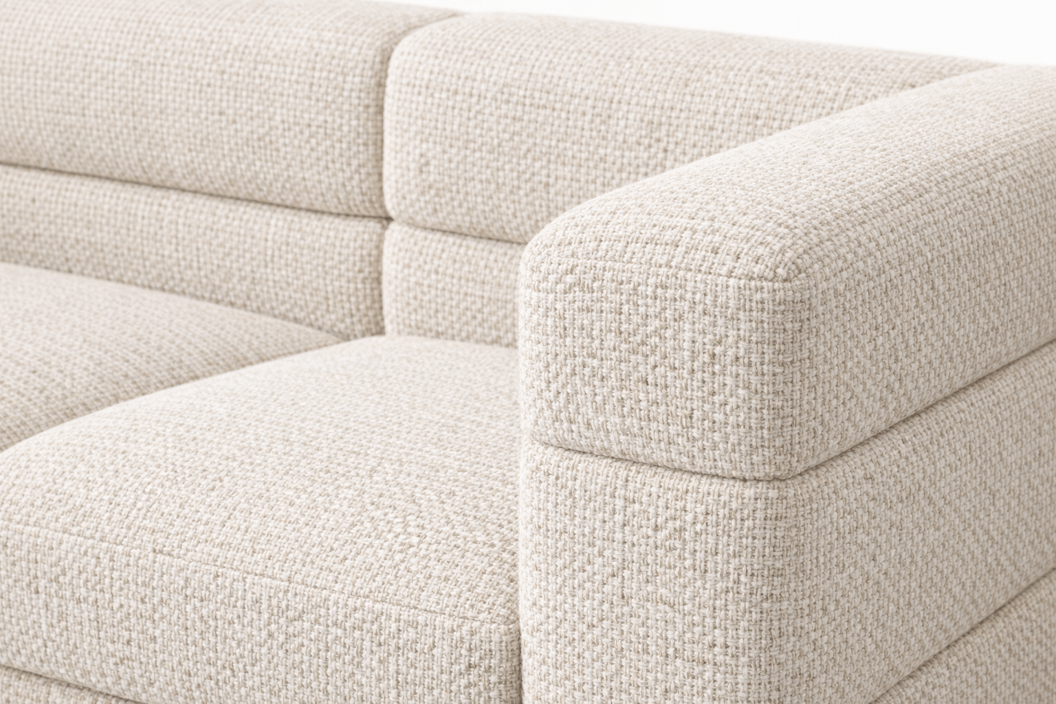 Close-up of a beige upholstered sofa with textured fabric and rounded armrest
