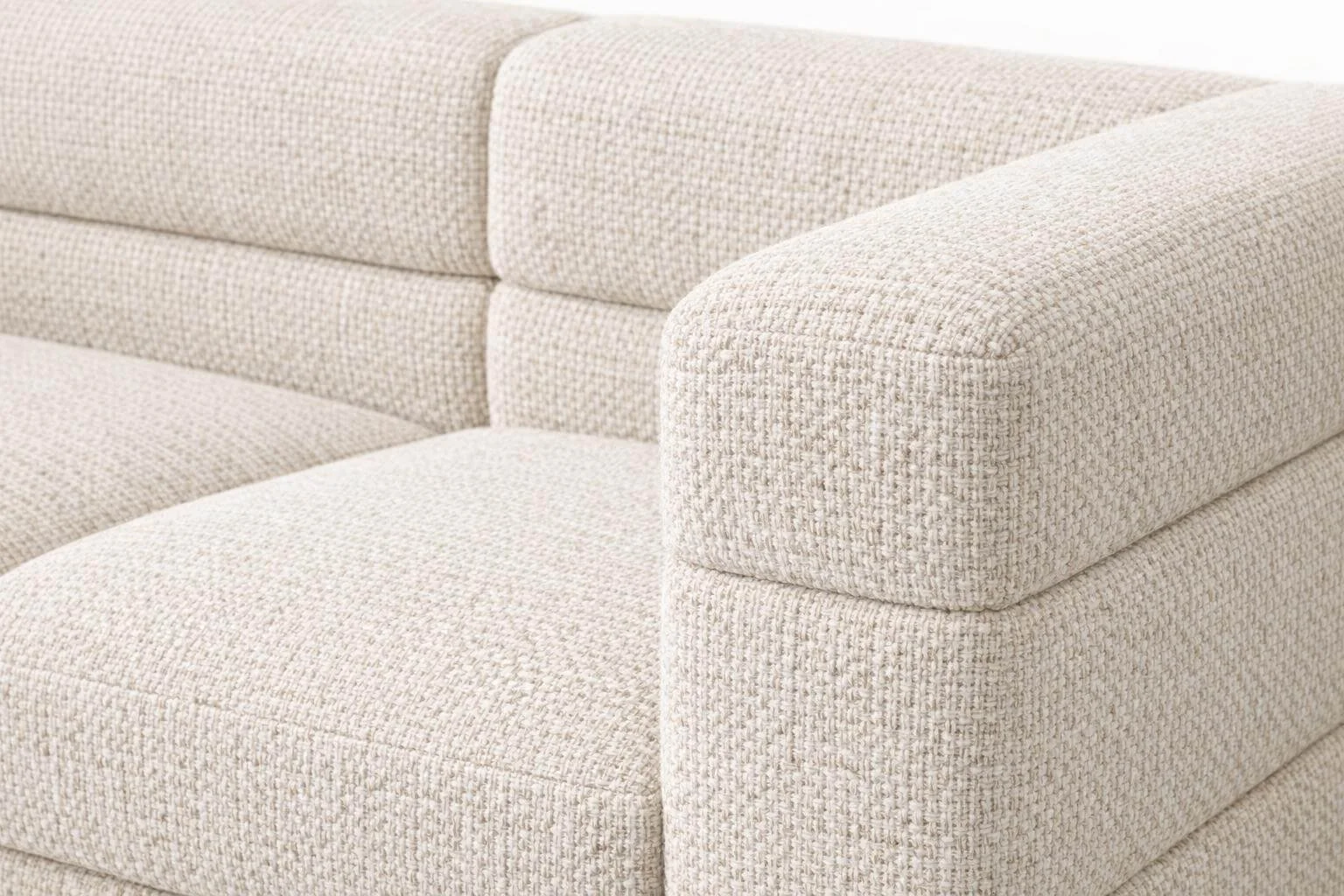 Close-up of a beige textured upholstered sofa with padded armrest and backrest.