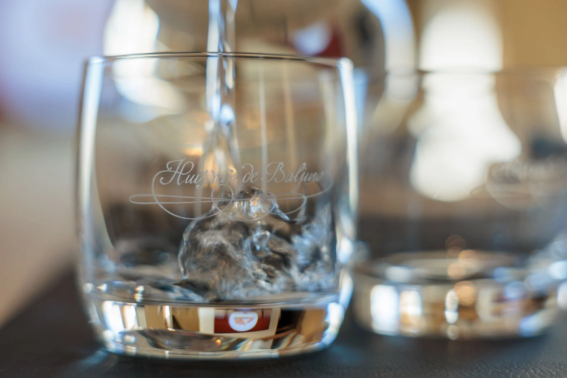 Close-up van een helder wijnglas met inscriptie 'Huis Van de Balju'