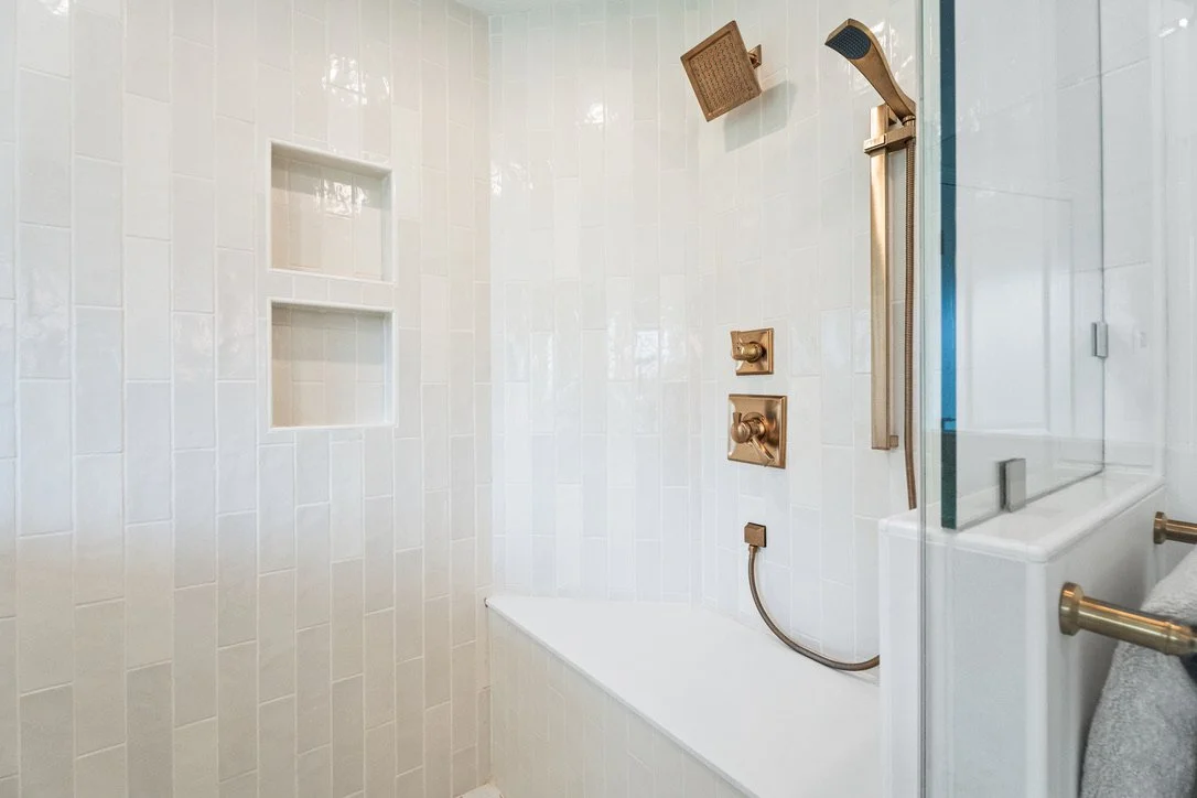 Walk-in shower with vertical tile, a built-in niche, and brass rainfall fixtures in a Brookville, Ohio master bathroom remodel.