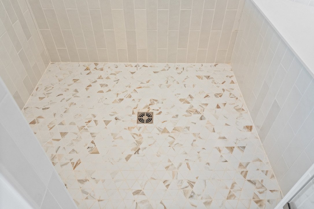 Terrazzo-style shower floor tile with a brass drain in a Brookville, Ohio bathroom renovation.