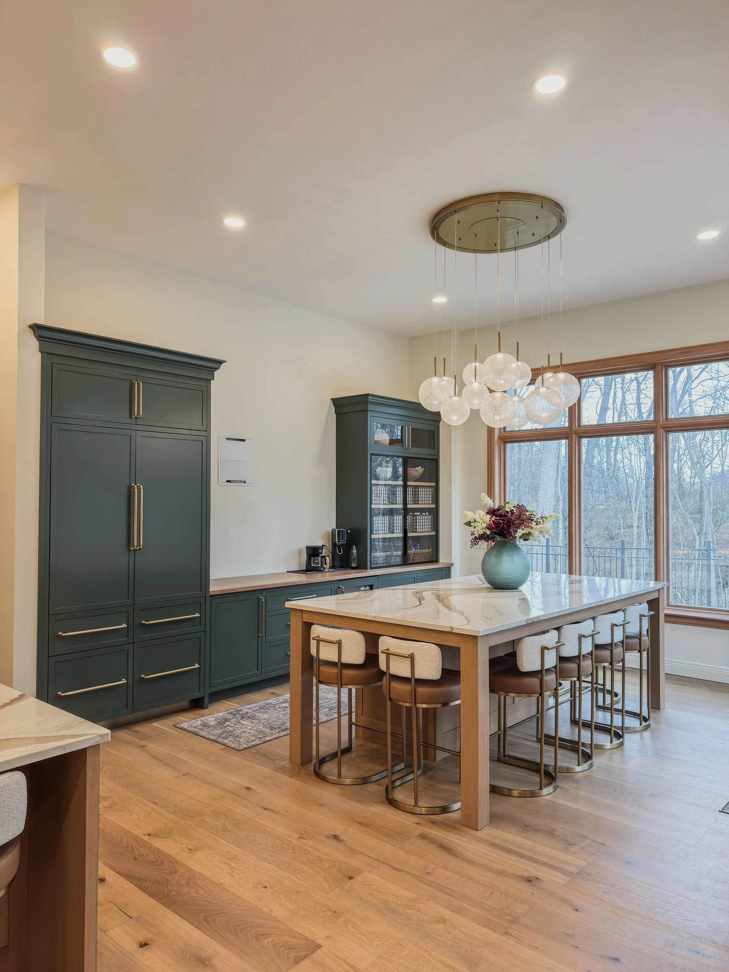 Bellbrook, Ohio dining and coffee bar area with green cabinetry, marble table, and statement glass chandelier by White Oak Interiors