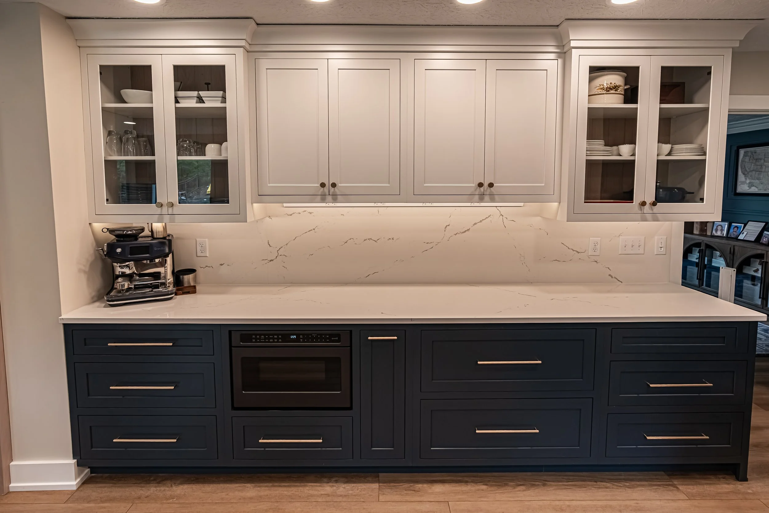 Kitchen with cream glass-front upper cabinets, navy lower cabinets, and a marble-look countertop in a Centerville remodel.
