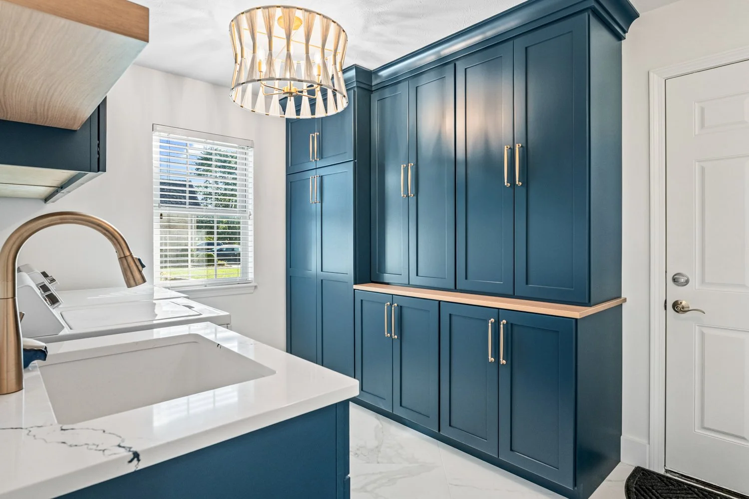 Mudroom with floor-to-ceiling navy blue cabinetry, brass pulls, and a wood counter in a Beavercreek, Ohio remodel.