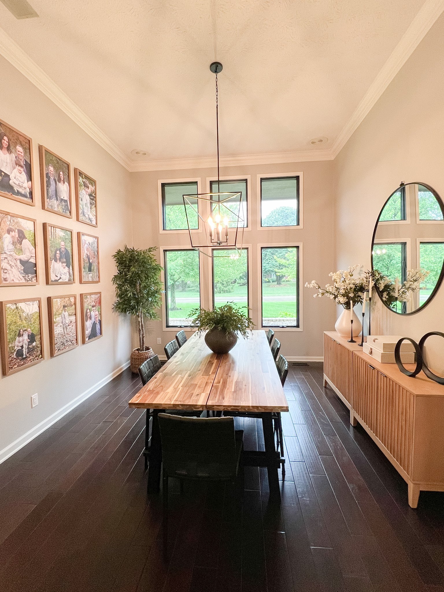 Dining room with a wood table, gallery wall, a wood sideboard with a round arched mirror, and dark wood flooring in a Centerville, Ohio renovation
