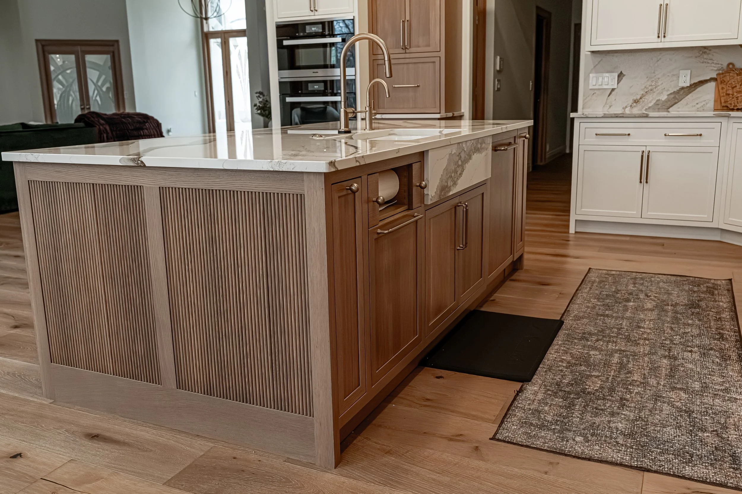 Kitchen island detail with prep sink, brass faucet, and fluted wood paneling in a Bellbrook, Ohio remodel