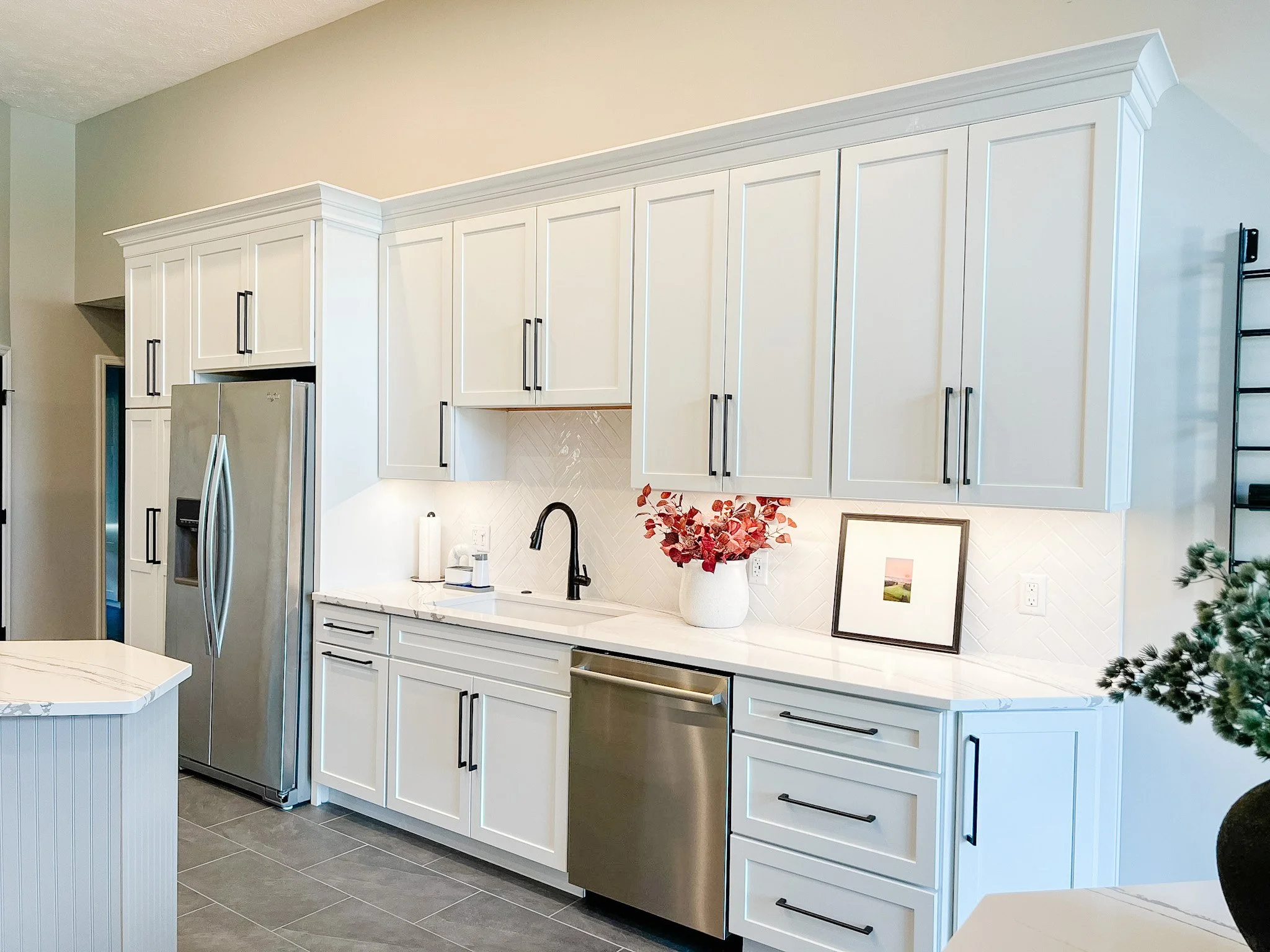 Renovated kitchen with white cabinetry to the ceiling, marble-look countertops, stainless appliances, and under-cabinet lighting in a Centerville, Ohio home