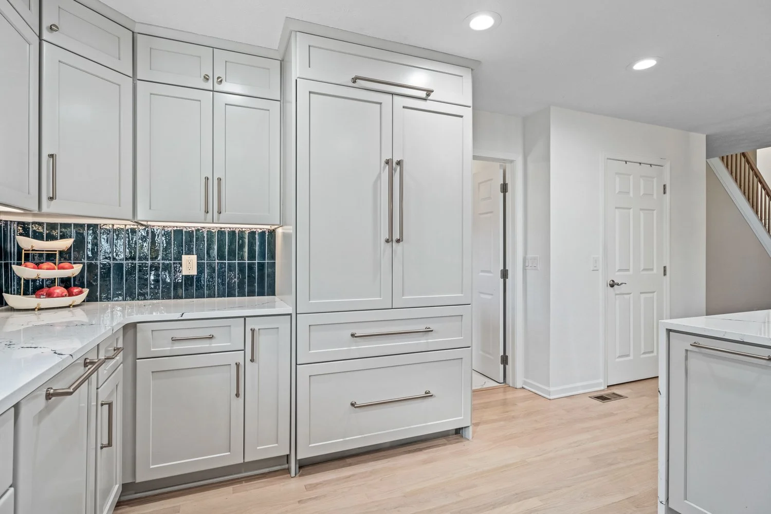 White shaker kitchen cabinetry with a paneled built-in refrigerator and quartz counters in a Beavercreek, Ohio remodel.