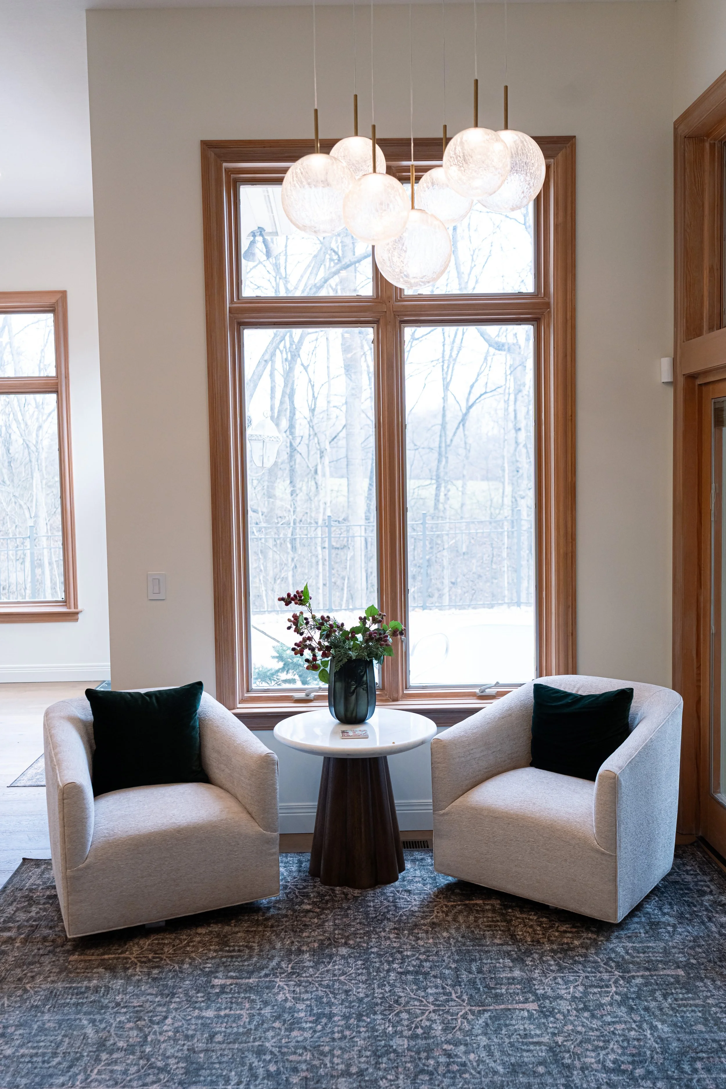 Open-concept living area off the kitchen in a Bellbrook, Ohio remodel, with upholstered swivel chairs, marble pedestal table, and large windows by White Oak Interiors