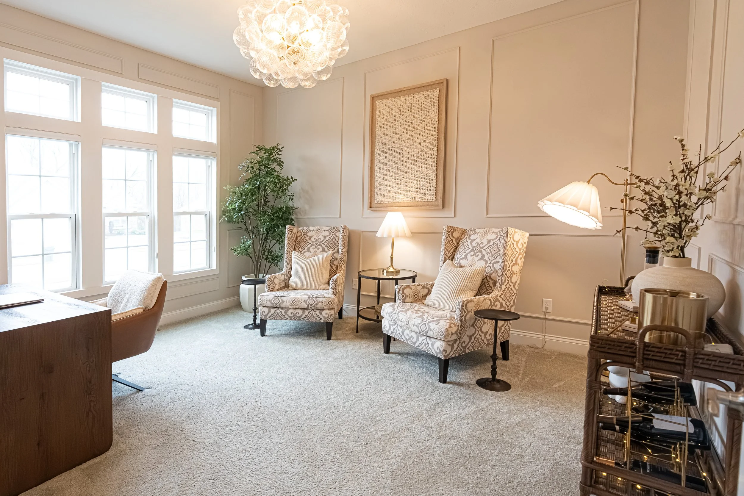 Formal sitting room with patterned wingback chairs and a beaded chandelier in a Centerville home renovation.