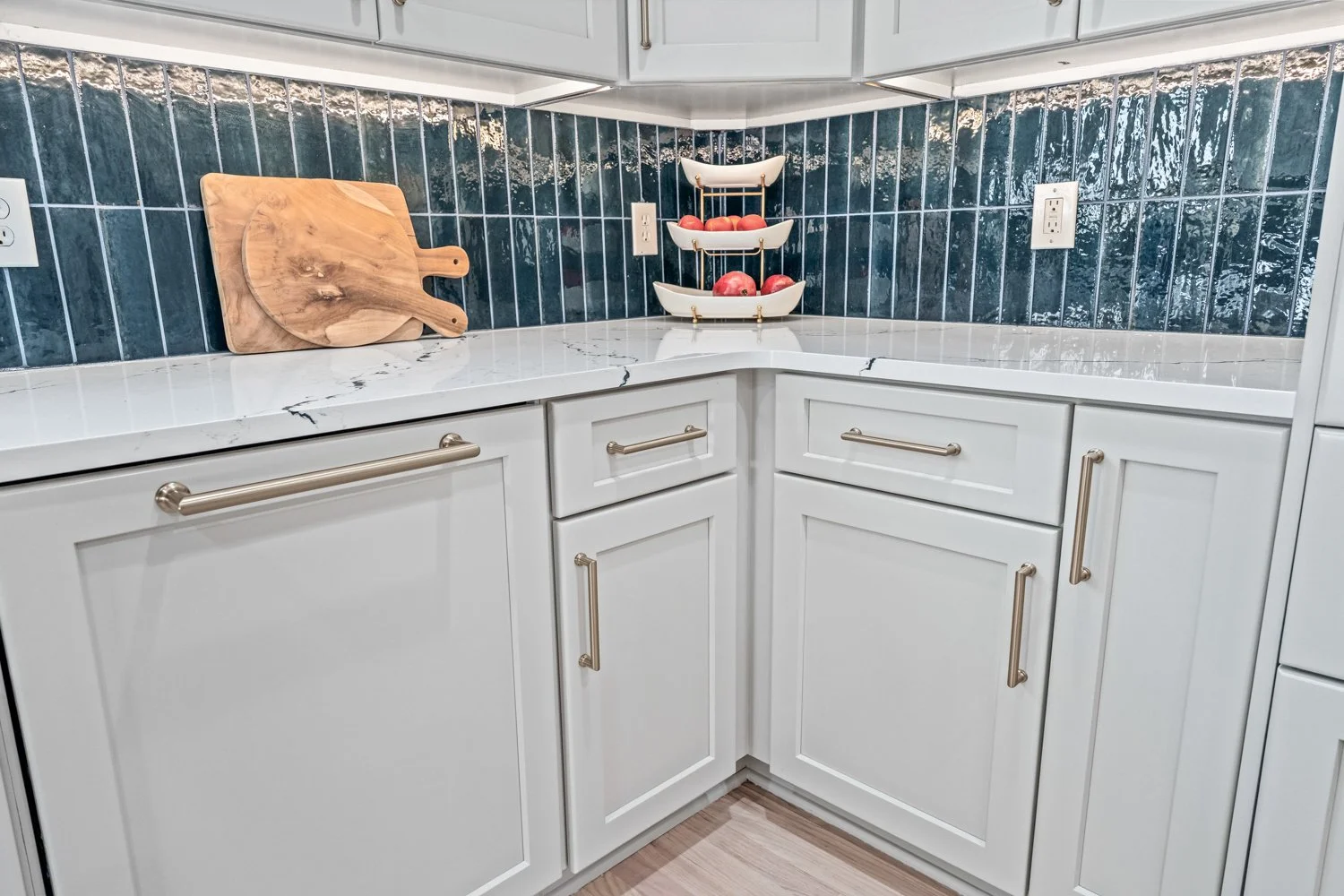White shaker kitchen corner with quartz counters and blue tile backsplash styled with wood cutting boards in a Beavercreek, Ohio remodel.