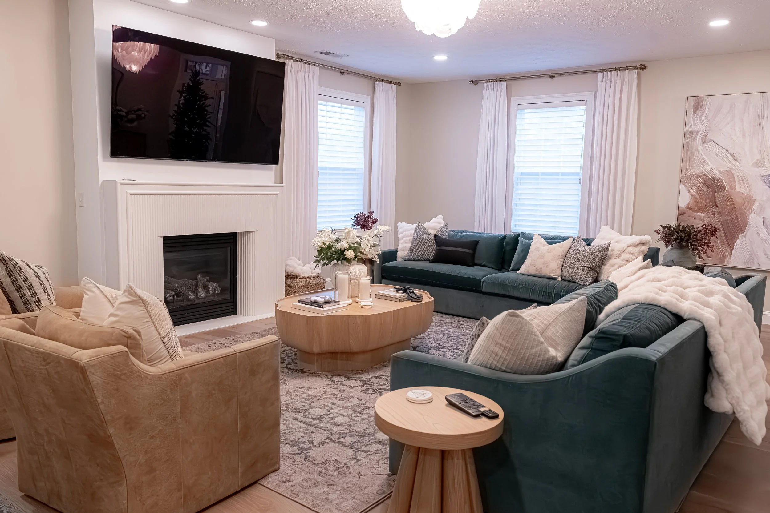 Renovated living room with a green velvet sectional, white fireplace, layered neutral textiles, and a round wood coffee table in Oakwood, Ohio