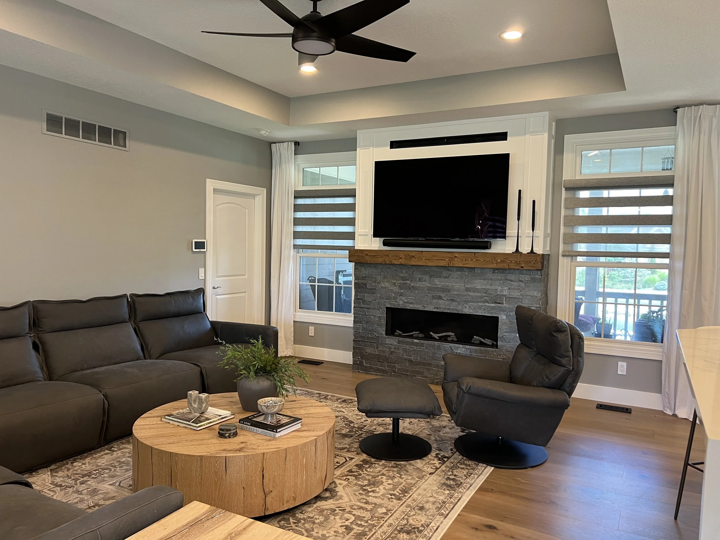 Living room with a floor-to-ceiling stone fireplace, wood mantel, sectional seating, and a tray ceiling in a Xenia, Ohio renovation