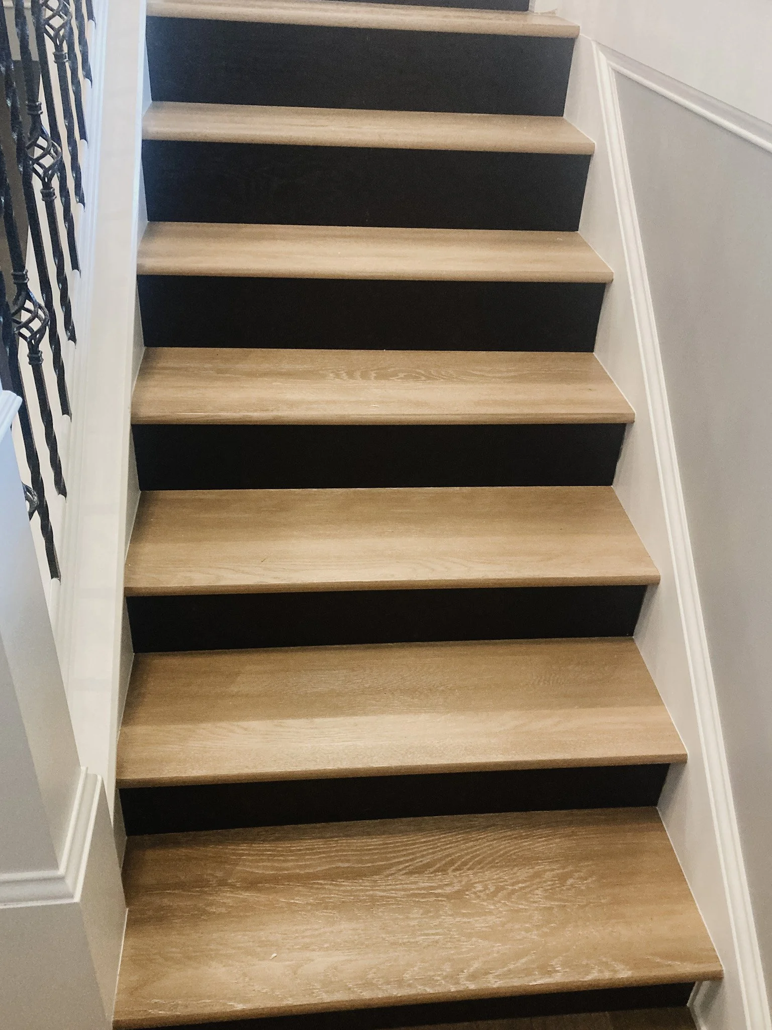 Renovated staircase with light wood treads, dark risers, and a black metal railing in a Xenia, Ohio home