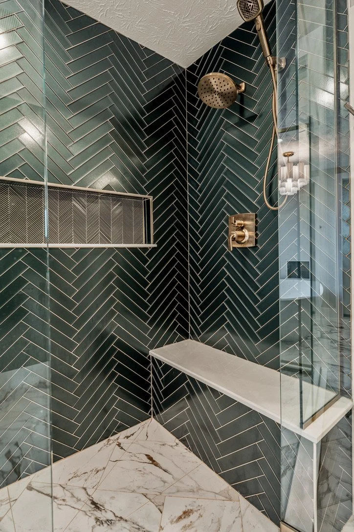 Walk-in shower interior with green herringbone tile, a floating stone bench, gold rainfall showerhead, and a custom niche in a Xenia, Ohio master bathroom