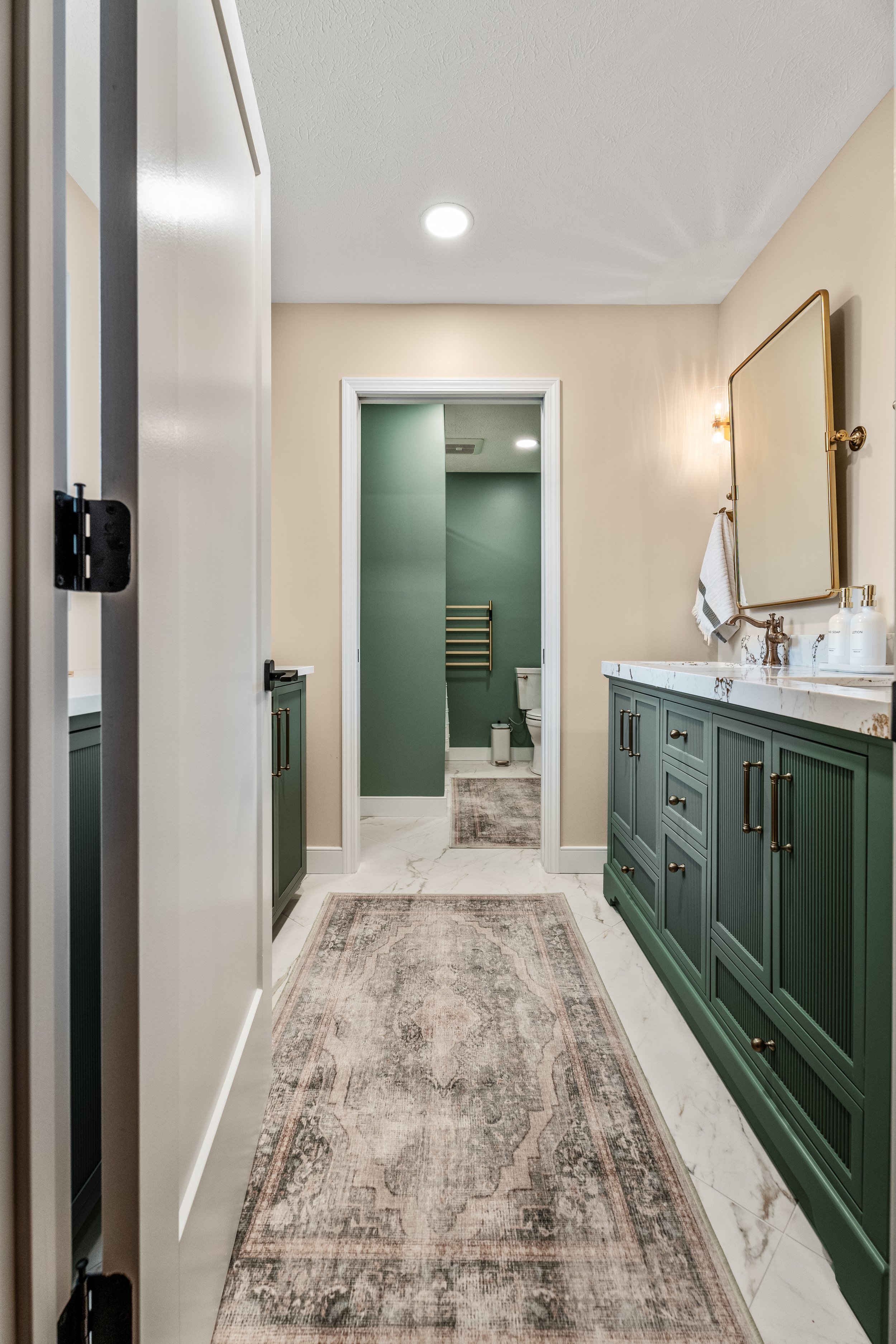 Basement bathroom in Centerville, Ohio with two-zone layout, green vanity, and separate shower room with towel warmer by White Oak Interiors