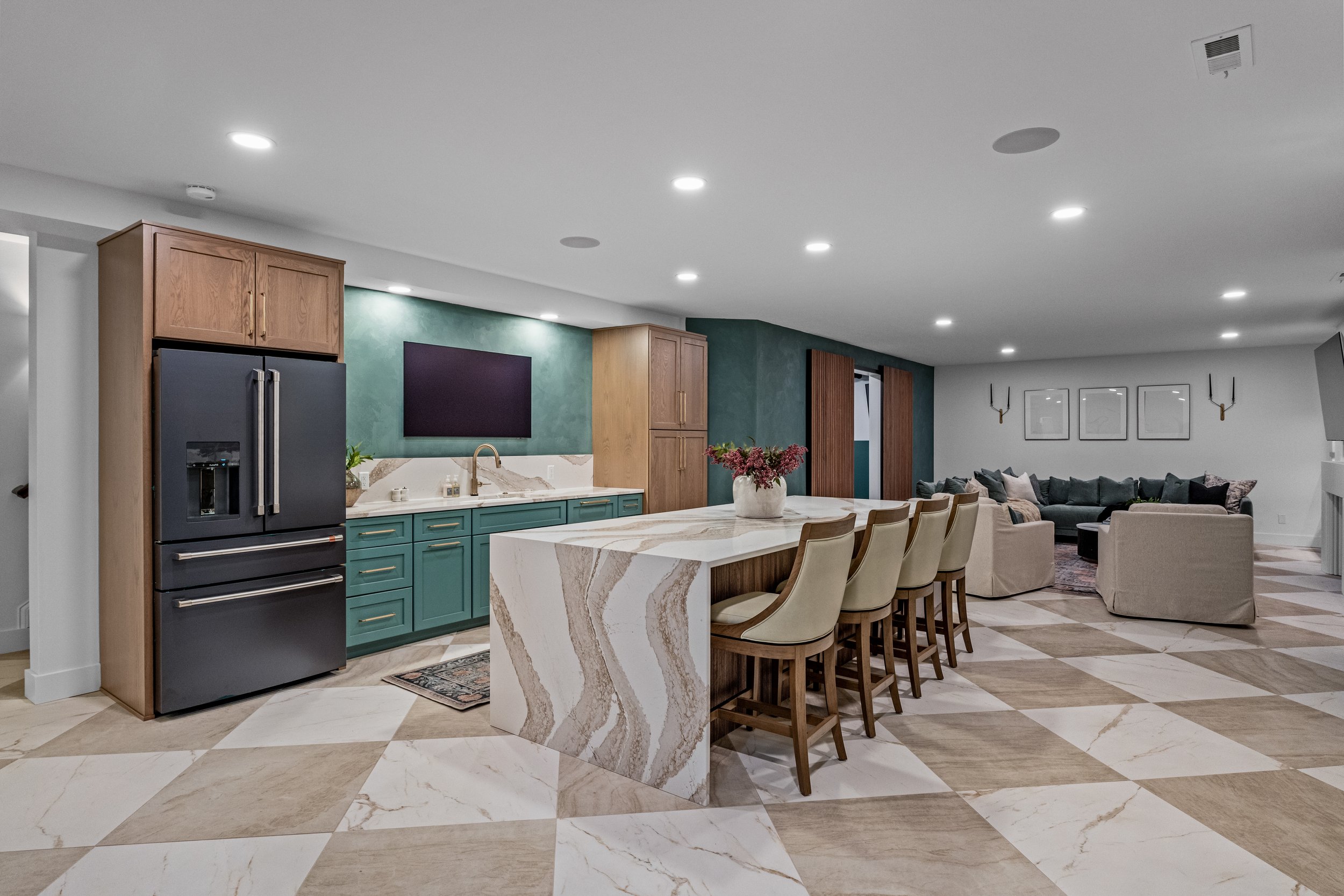 Open-concept finished basement with a custom kitchen, marble waterfall island, and living area in the Dayton, Ohio area by White Oak Interiors