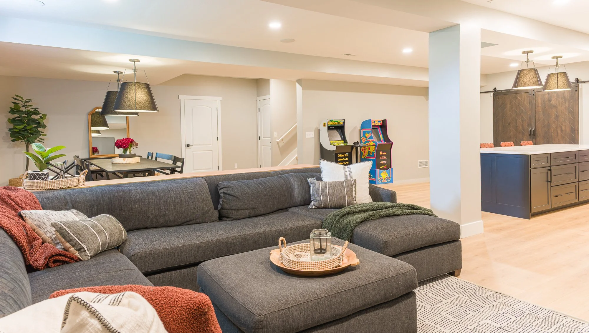 Open basement lounge with seating, arcade game area, and wet bar in a Dayton-area finished basement