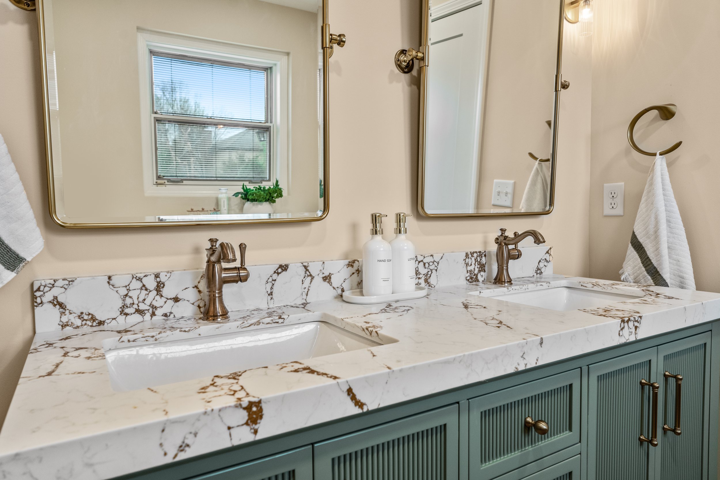 Basement bathroom vanity detail in Centerville, Ohio with marble countertop, gold faucet, and undermount sink by White Oak Interiors