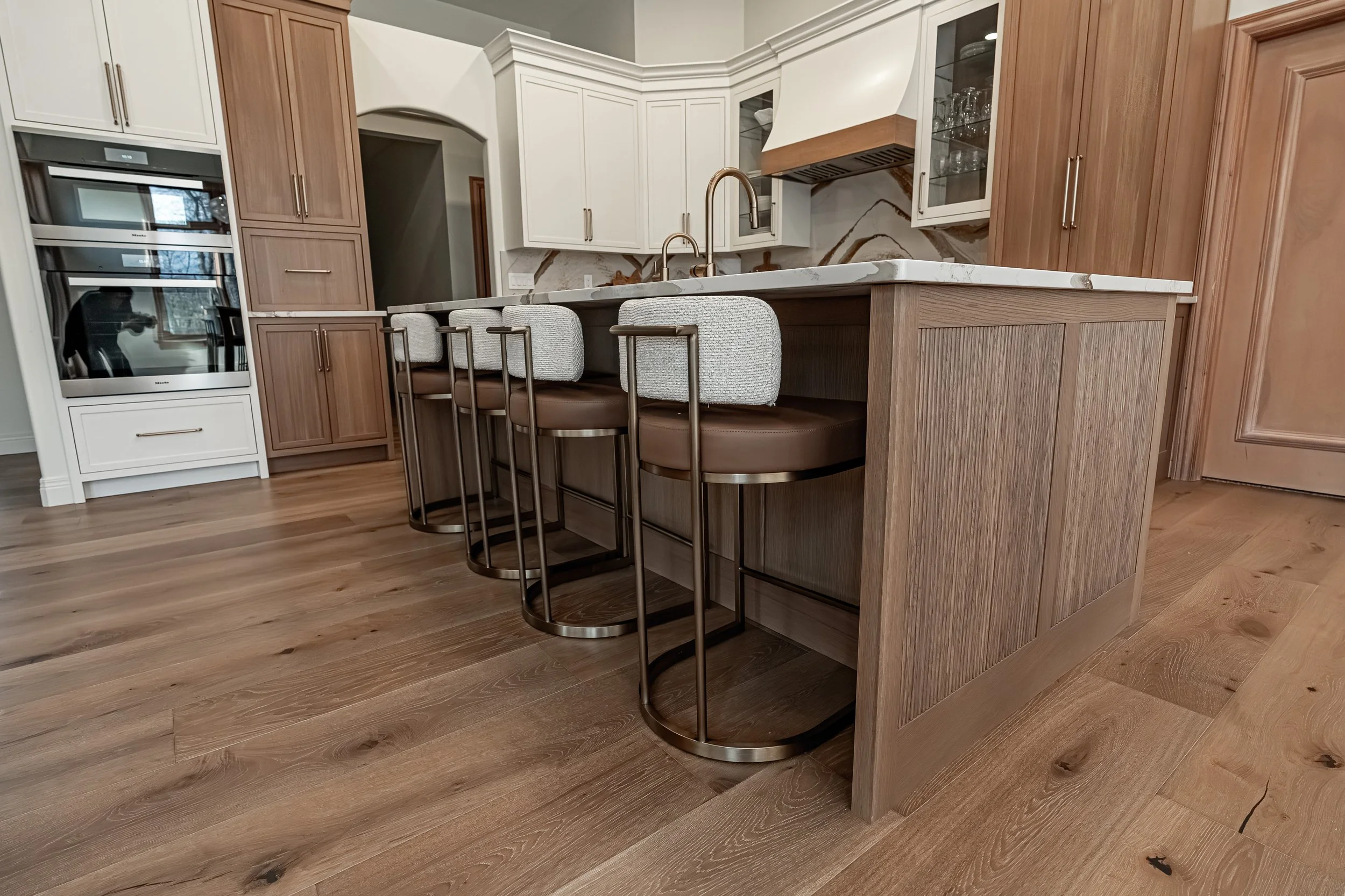 Custom fluted wood kitchen island with leather and bouclé bar stools in a Bellbrook, Ohio kitchen remodel