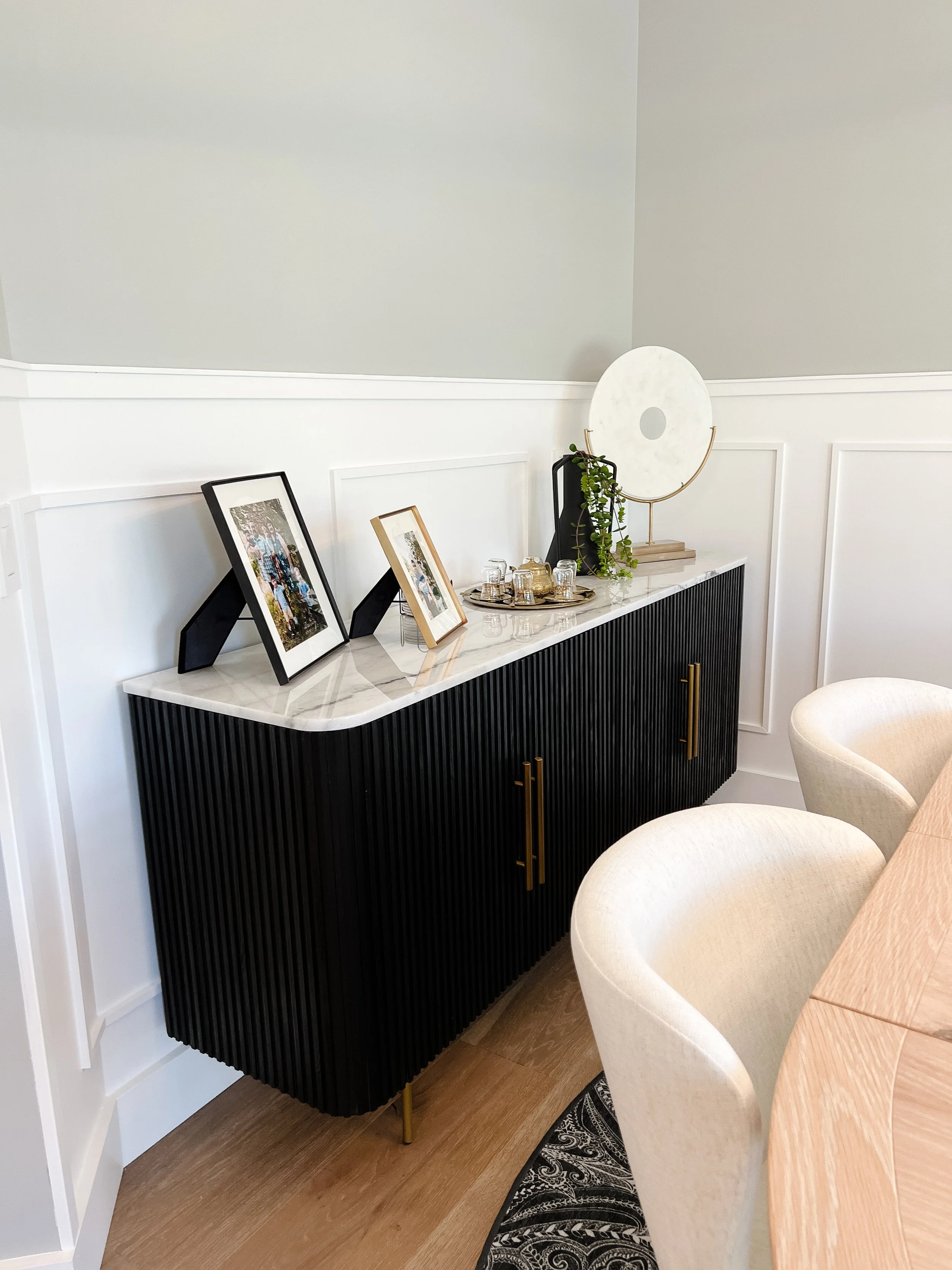 Dining area detail with a black reeded sideboard, quartz top, gold hardware, and styled decor against board-and-batten wainscoting in a Xenia, Ohio home